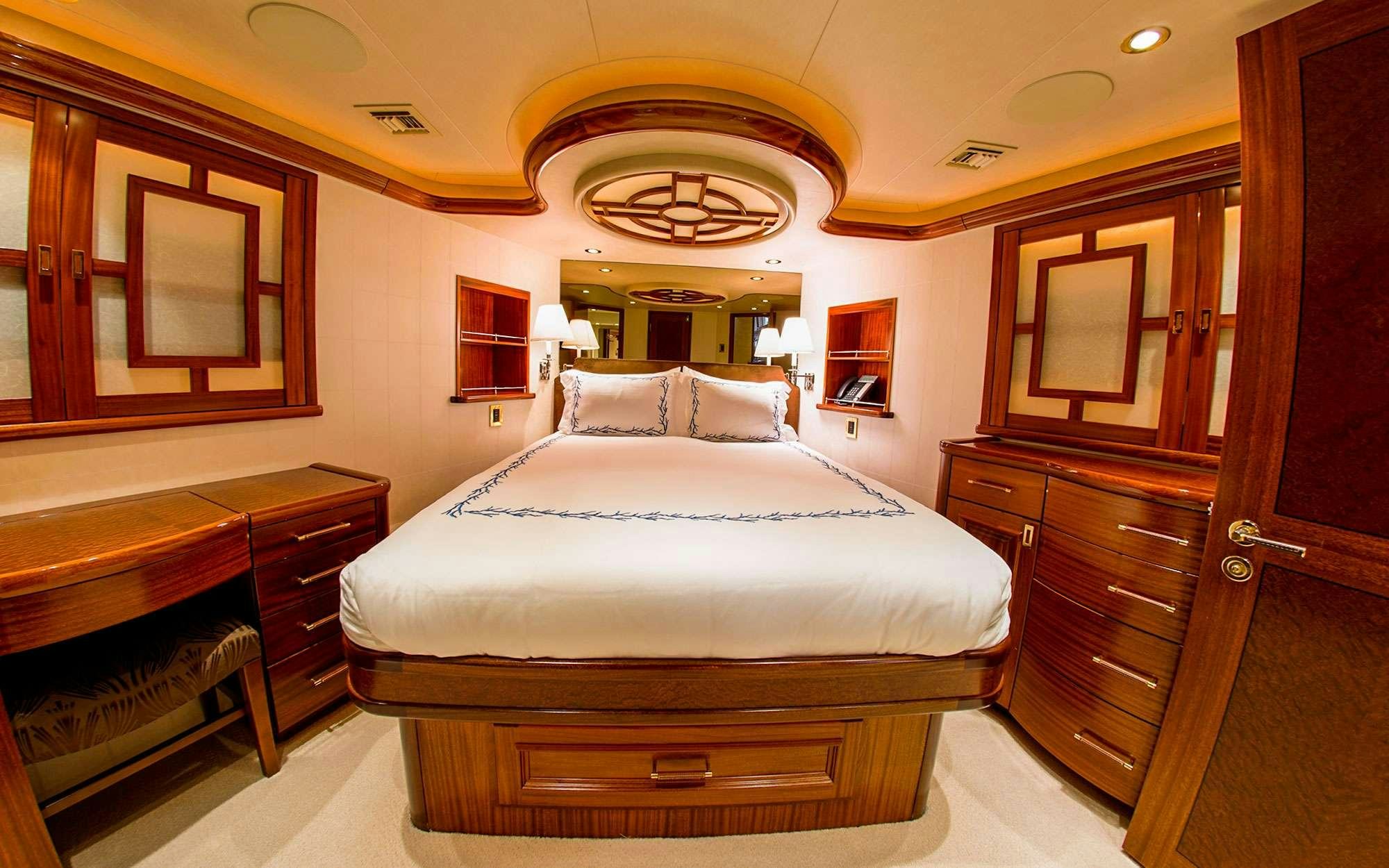 a bedroom with a bed and dresser aboard JEANNIETINI Yacht for Charter