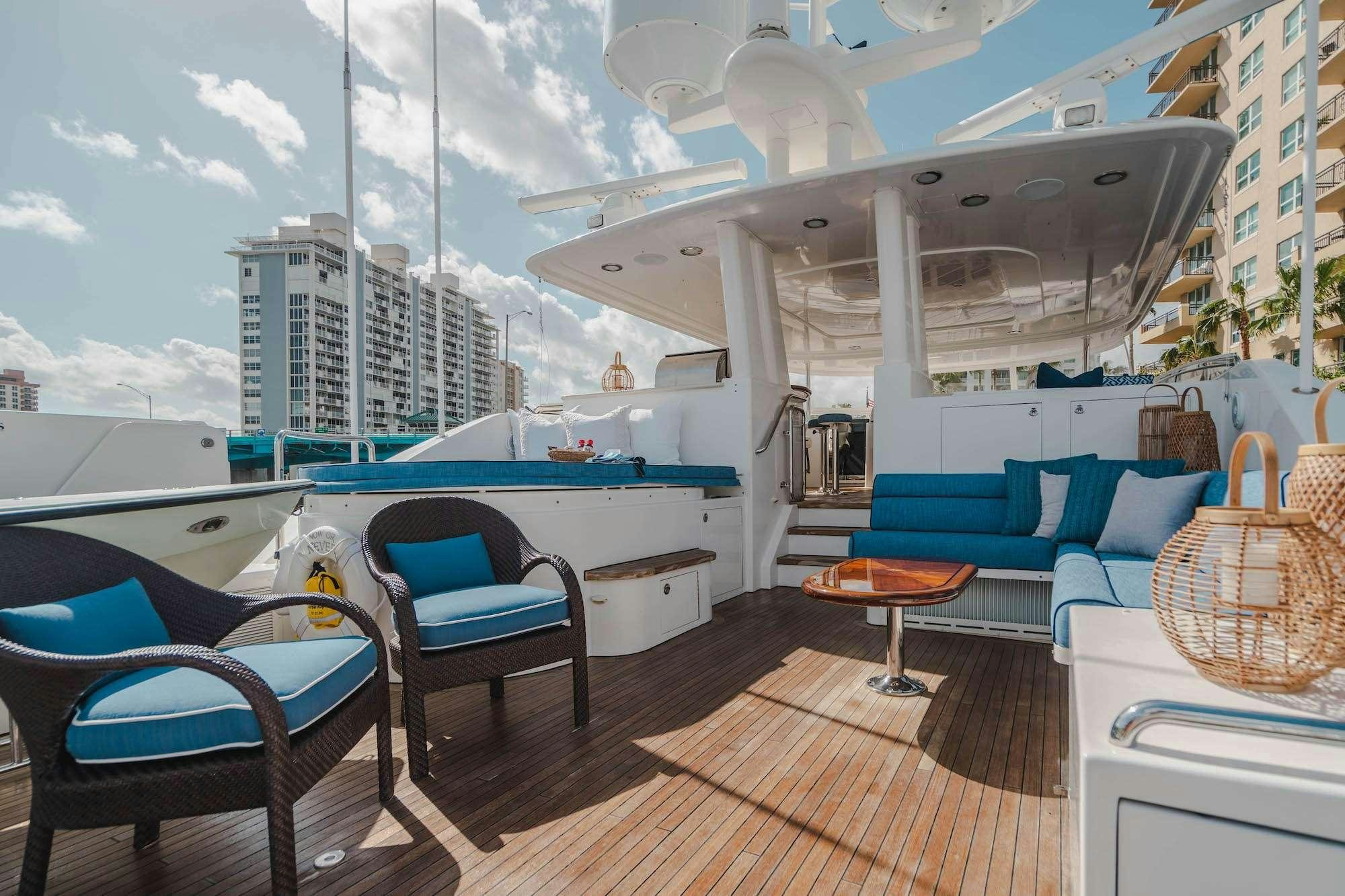 a large white boat with a deck and chairs on a deck aboard NOW OR NEVER Yacht for Charter