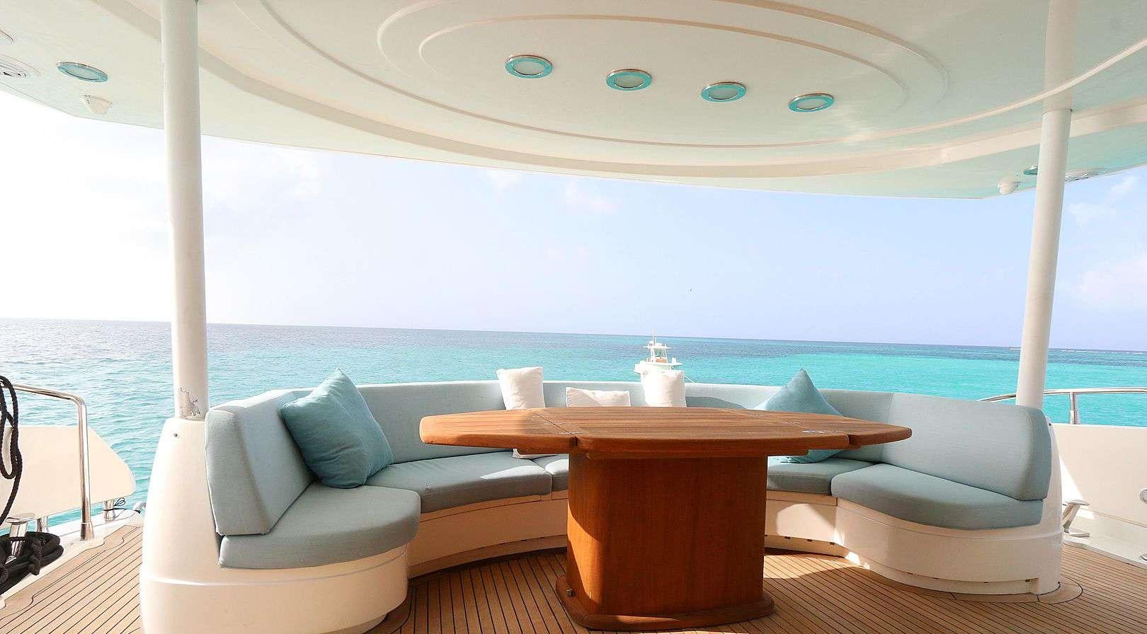 a room with a table and a couch and a large window aboard YCM 105 Yacht for Charter