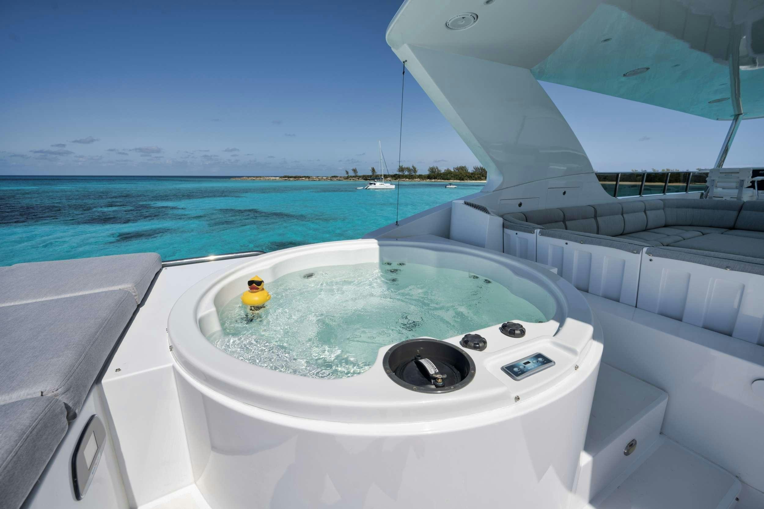 a white bathtub with a rubber duck in it by a large body of water aboard LIMITLESS Yacht for Charter