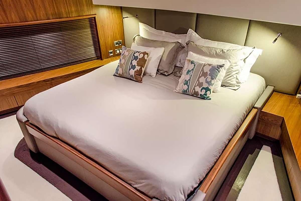 a bed with white sheets and pillows aboard EMRYS Yacht for Charter