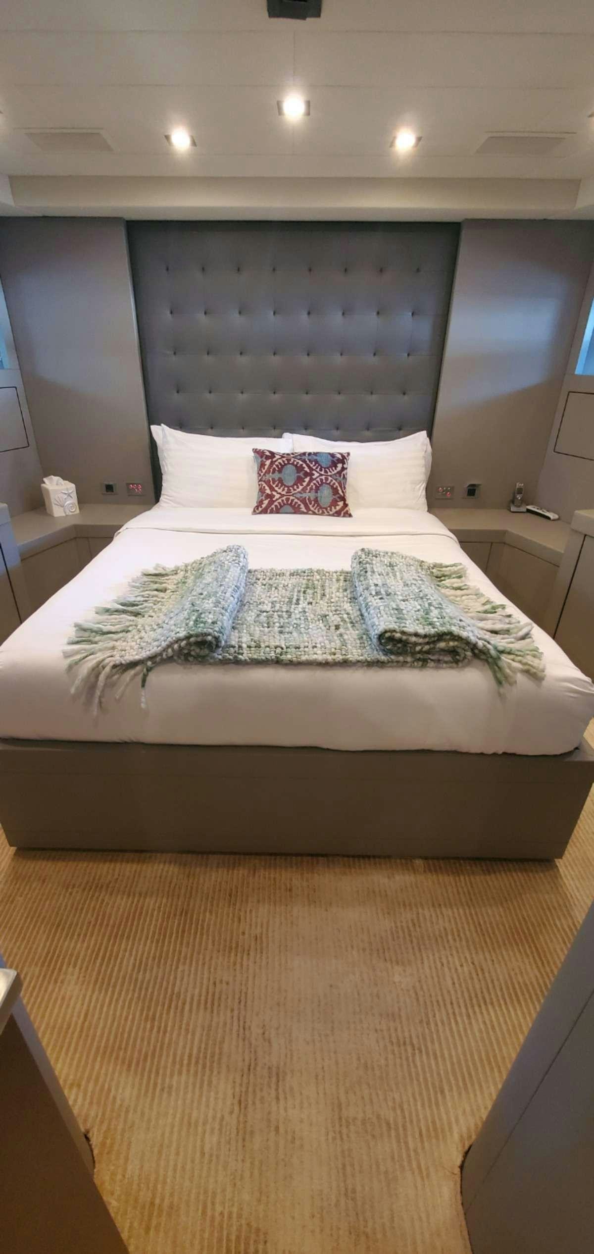 a bed with a blue and white comforter and pillows aboard HOUDINI Yacht for Charter