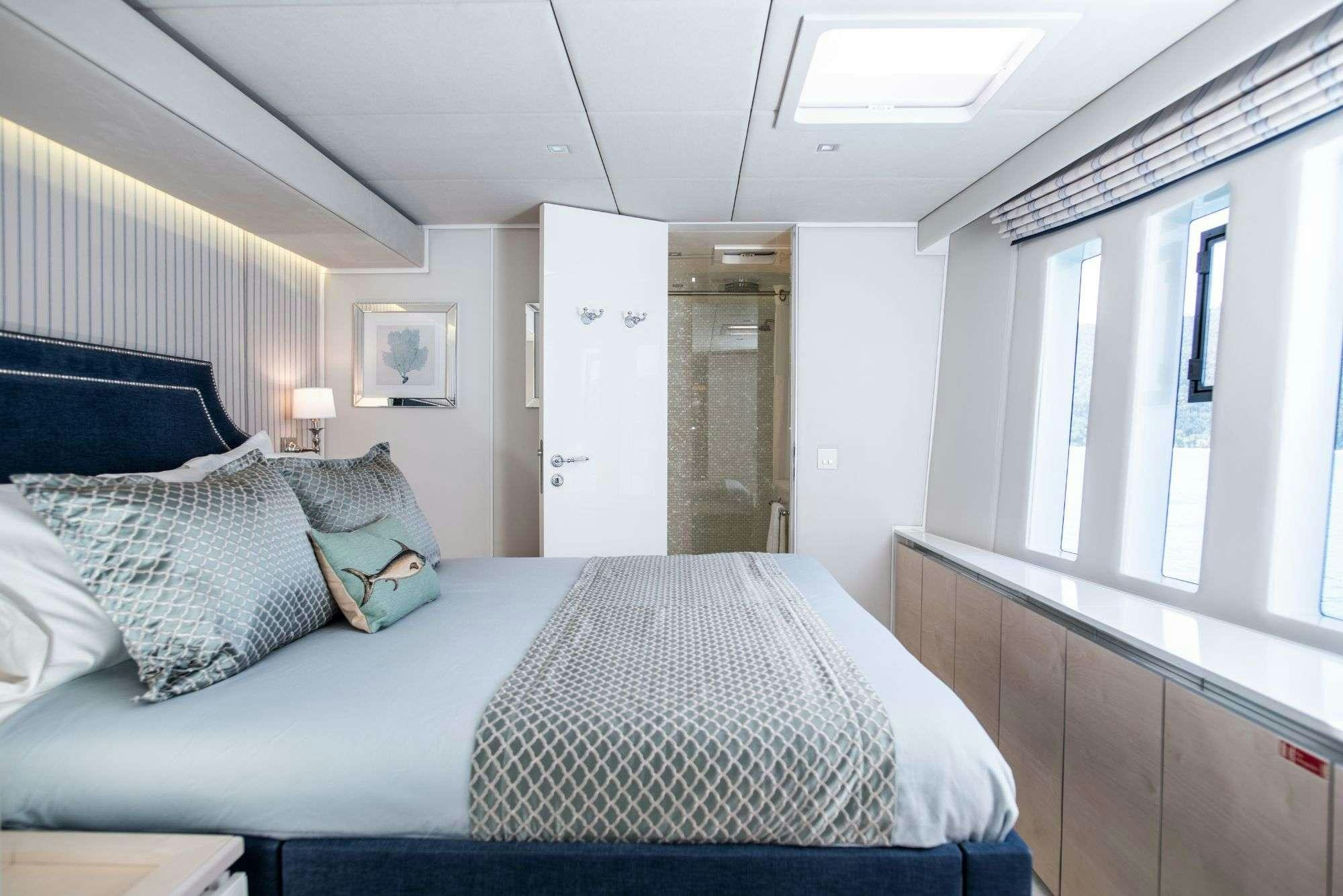 a bedroom with a bed and a window aboard BUNDALONG Yacht for Charter