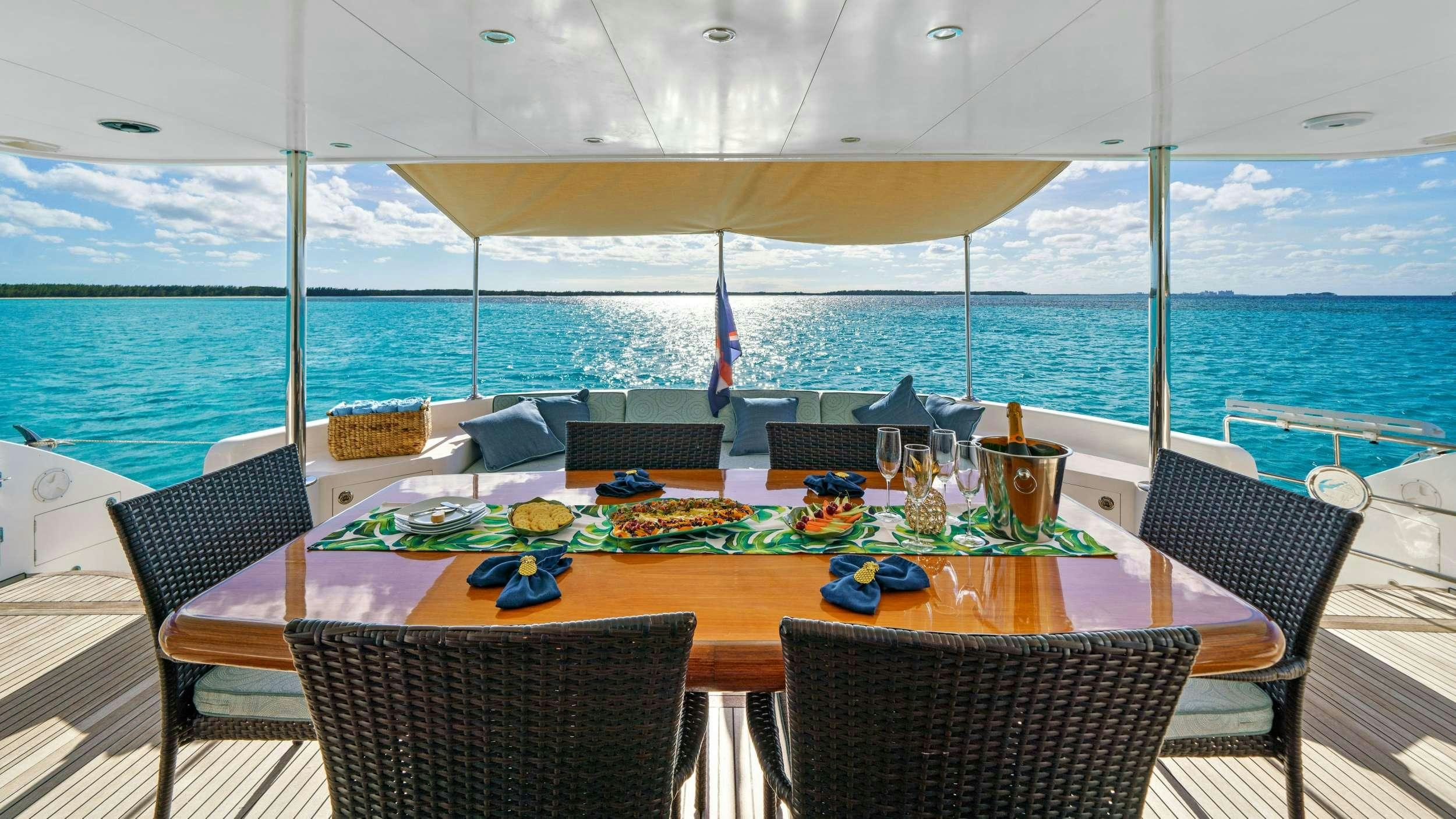 a table set for a meal on a deck with a view of the ocean aboard INDIGO Yacht for Charter