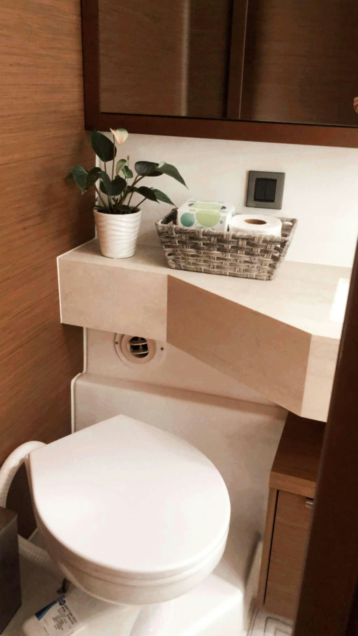 a bathroom with a toilet and a basket on the counter aboard MARCH DRAGON Yacht for Charter
