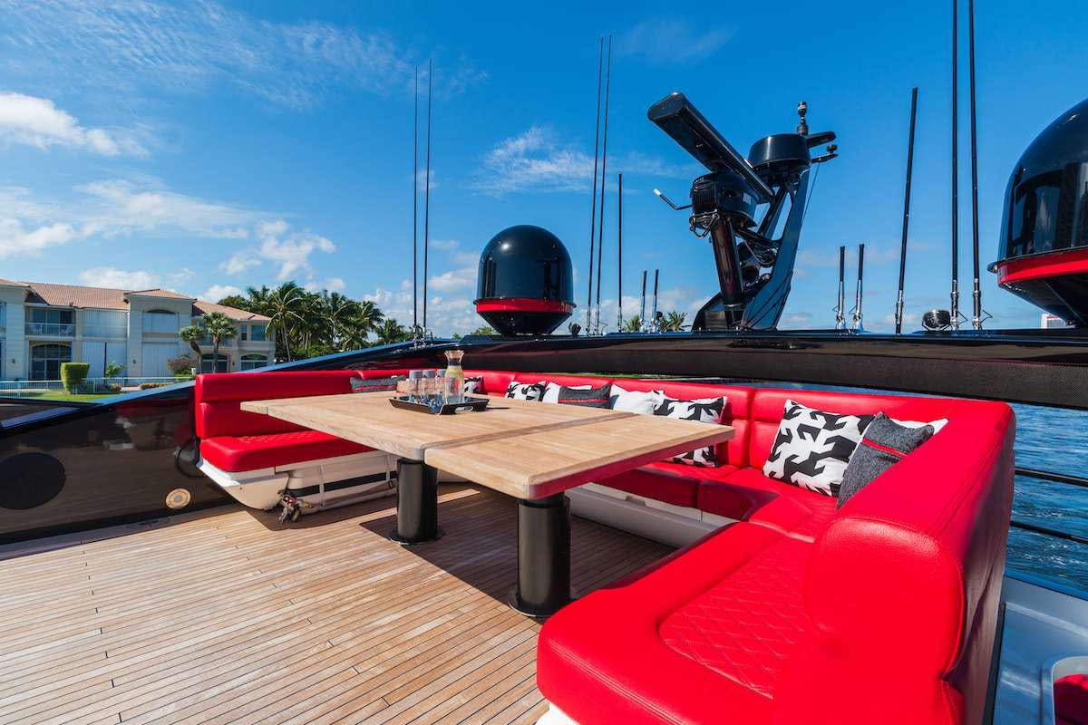 a red and black boat on a dock with a black object on it aboard CANELO Yacht for Charter