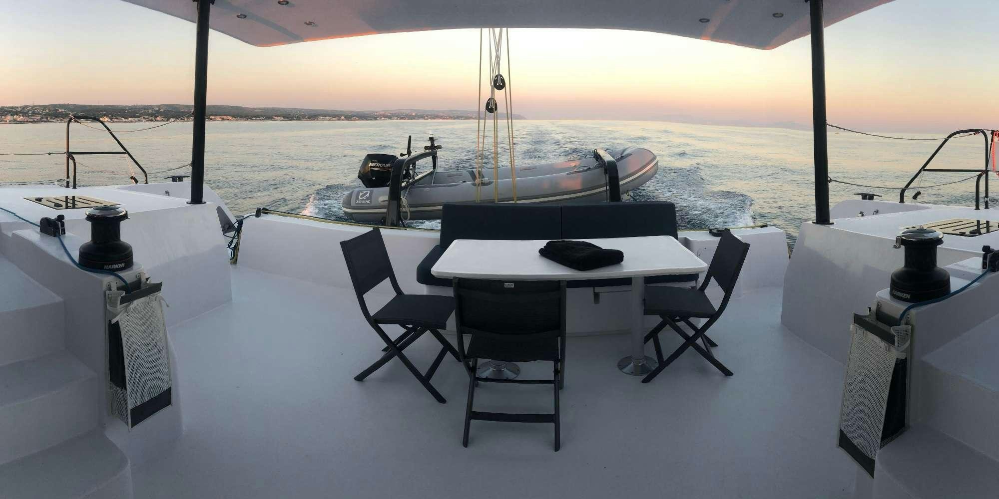 a table and chairs on a deck overlooking a body of water aboard GIVE ME FIVE Yacht for Charter