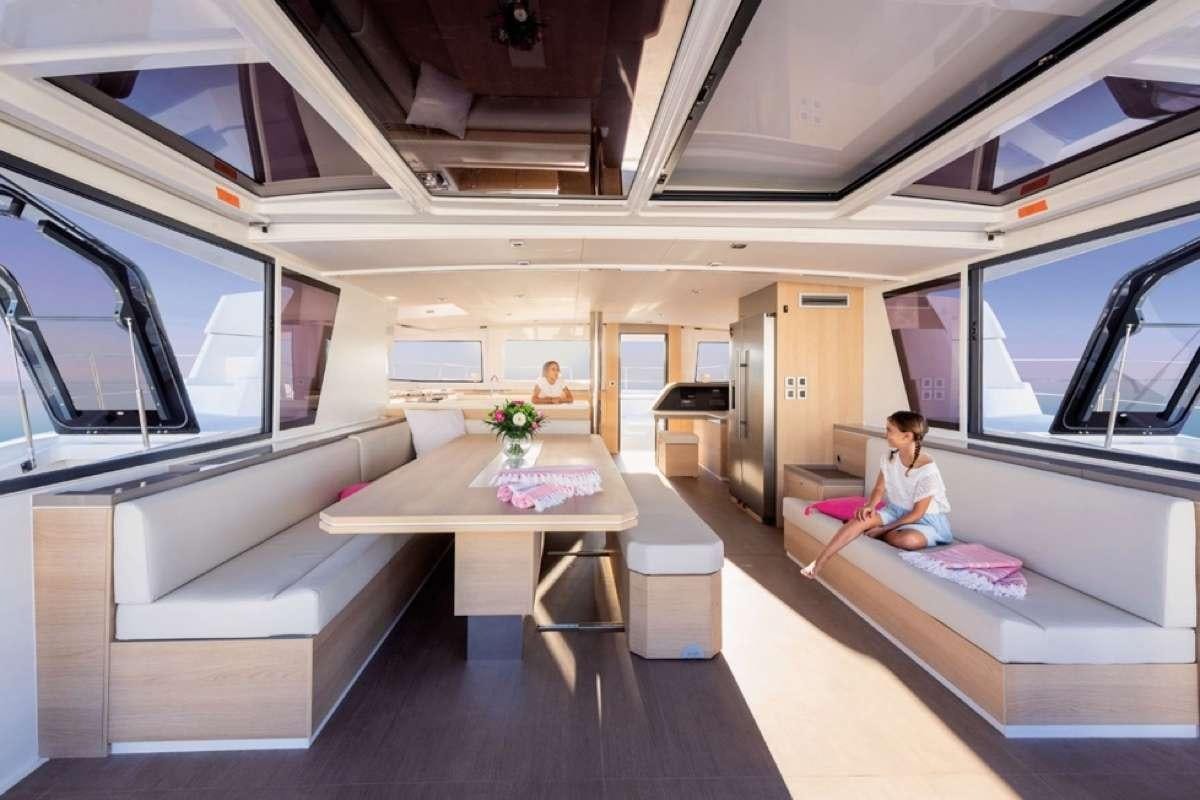 a person sitting on a couch in a room with a table and a window aboard Crystal Dreams Yacht for Charter