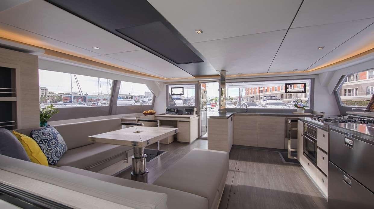 a large kitchen with a table and a couch aboard Atumavu Yacht for Charter