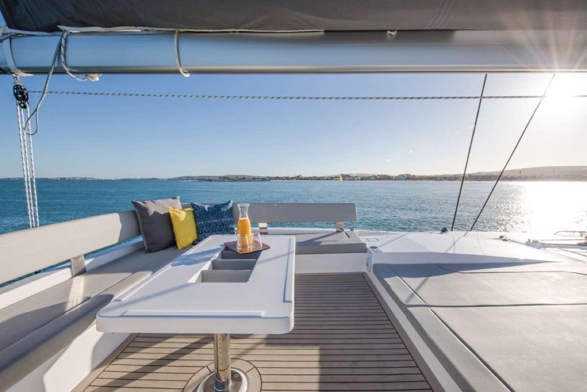 a deck with a view of the ocean and a beach aboard Atumavu Yacht for Charter