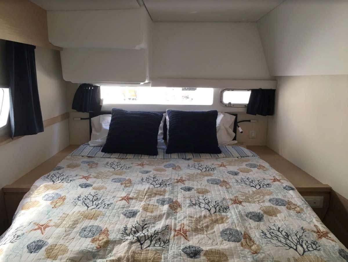 a bed with a blue and white comforter and pillows aboard Heliades Yacht for Charter