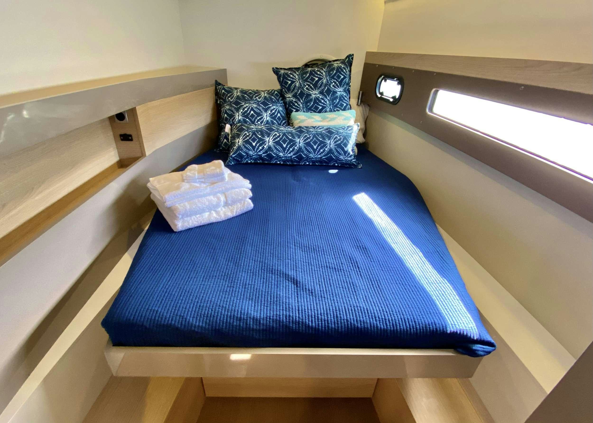 a bed with a blue blanket on it aboard FREESTYLE Yacht for Charter