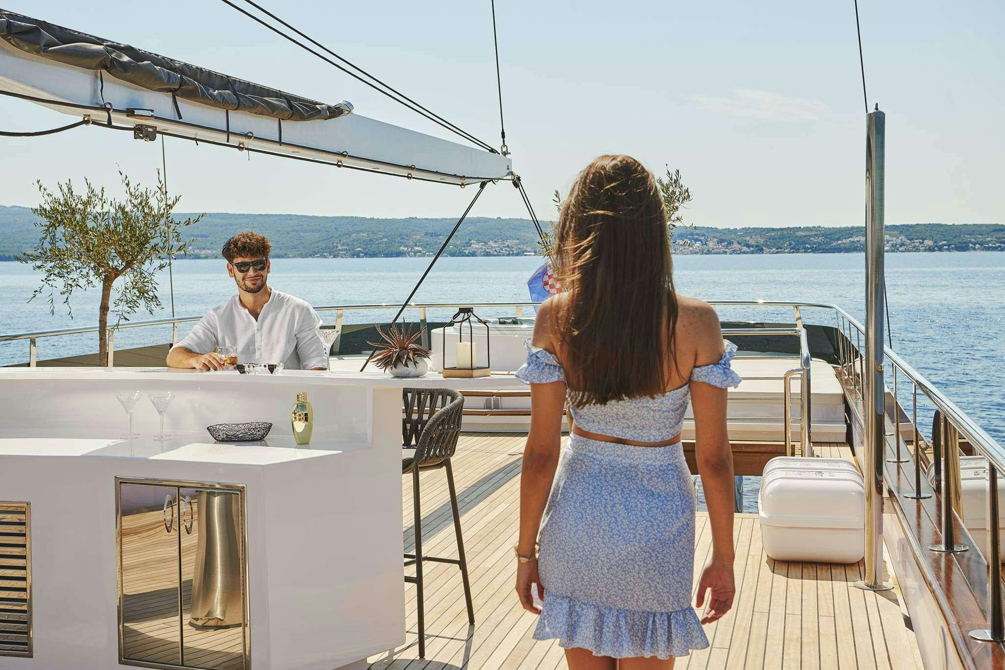 a man and woman sitting on a deck overlooking a body of water aboard ANIMA MARIS Yacht for Charter