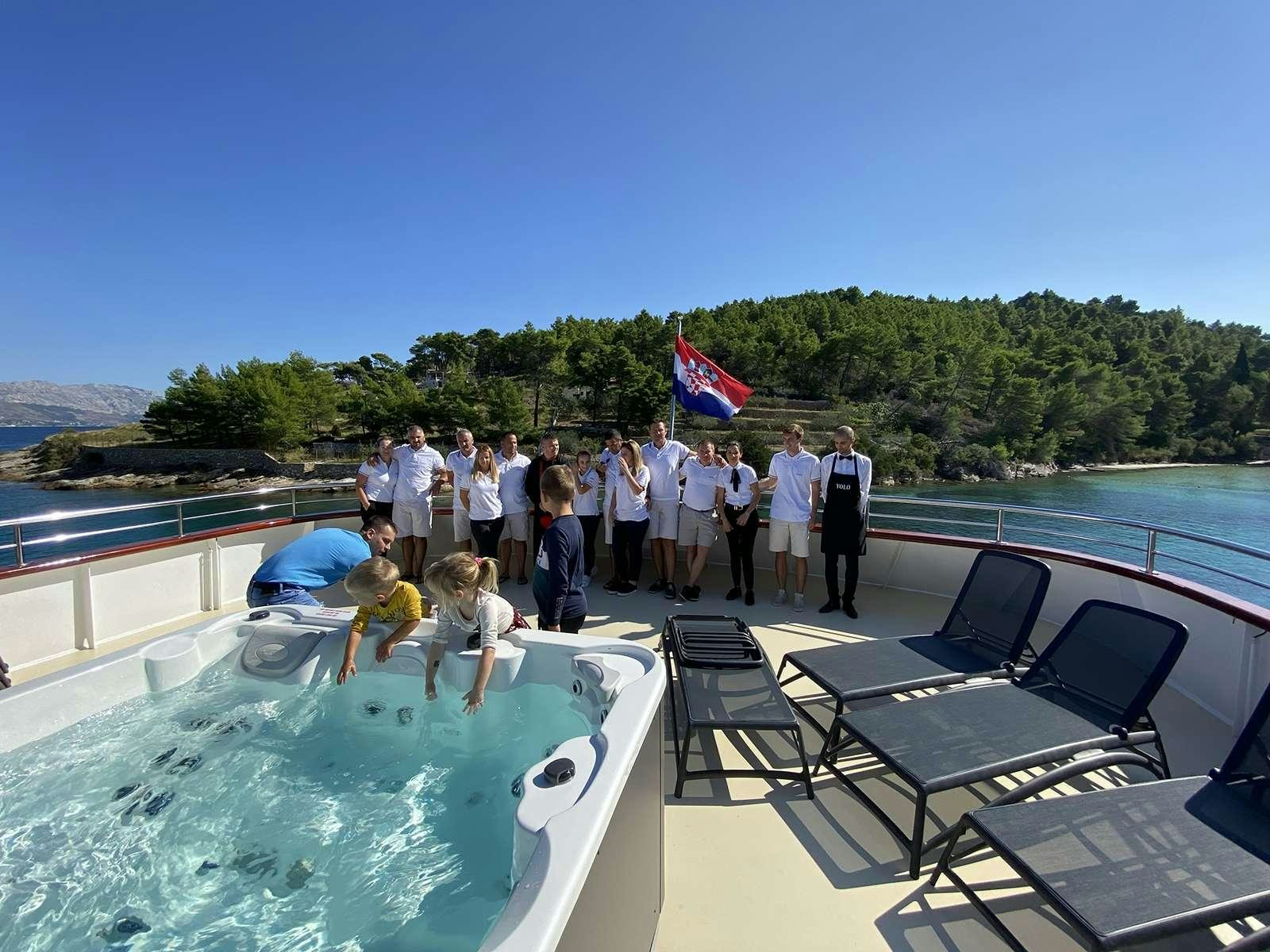 a group of people standing around a pool of water aboard YOLO Yacht for Charter