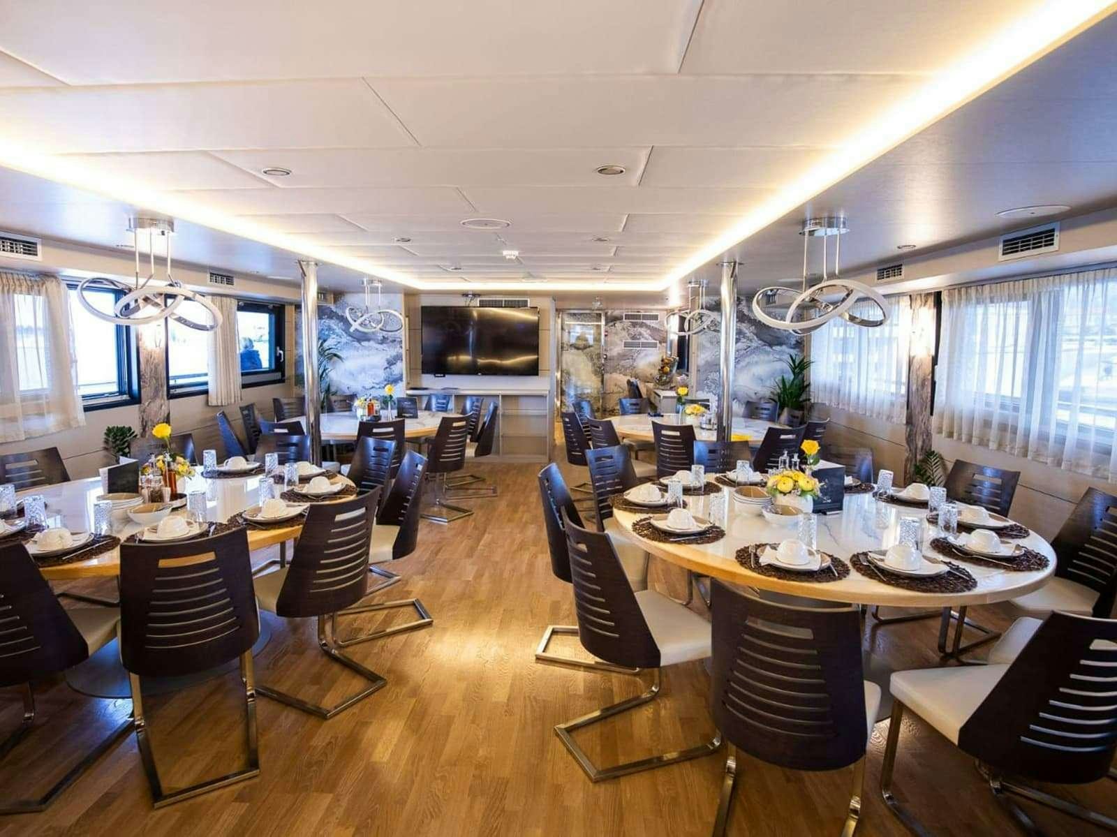 a room with tables and chairs aboard FREEDOM Yacht for Charter
