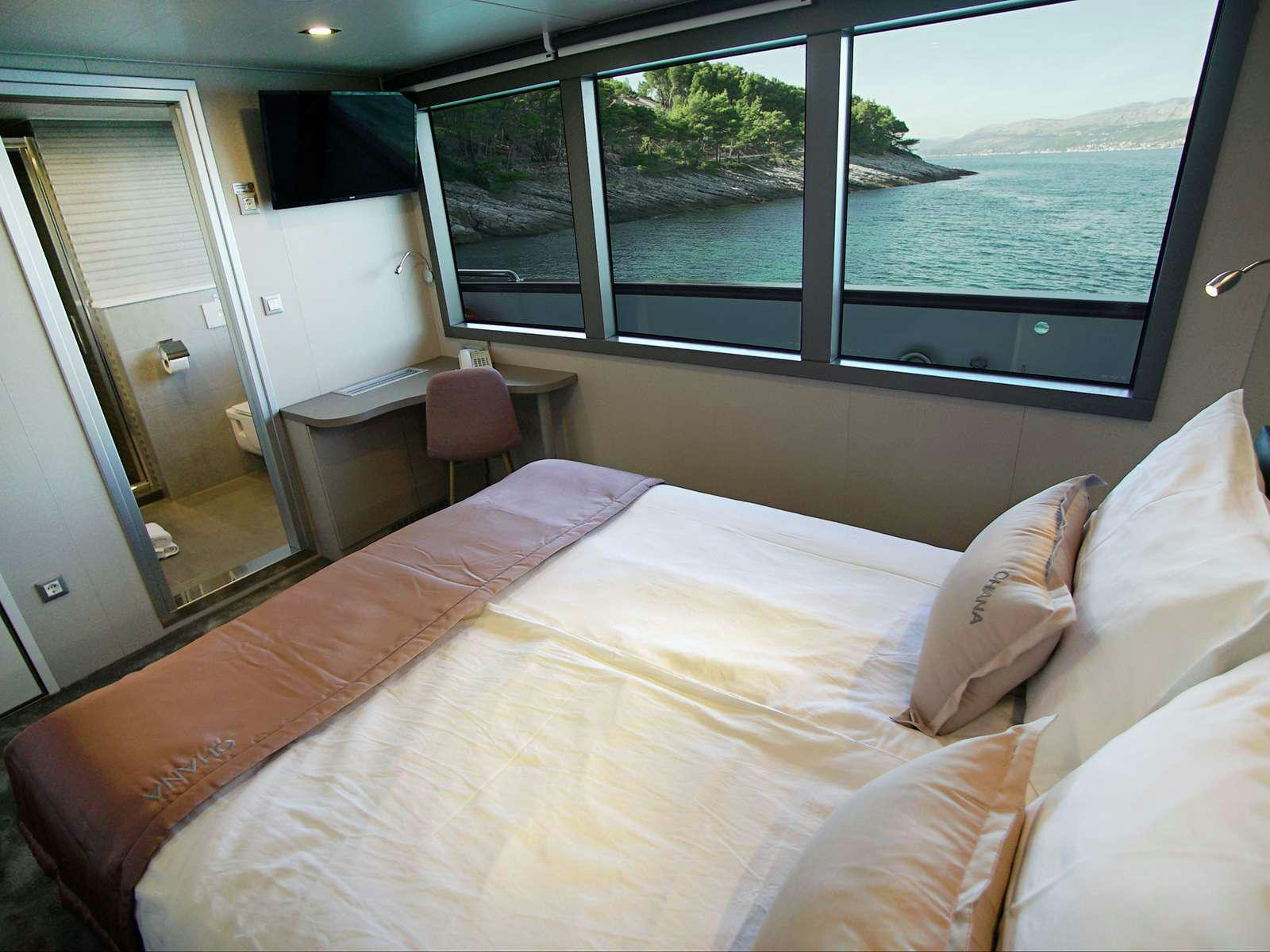 a bed with a large window aboard OHANA Yacht for Charter