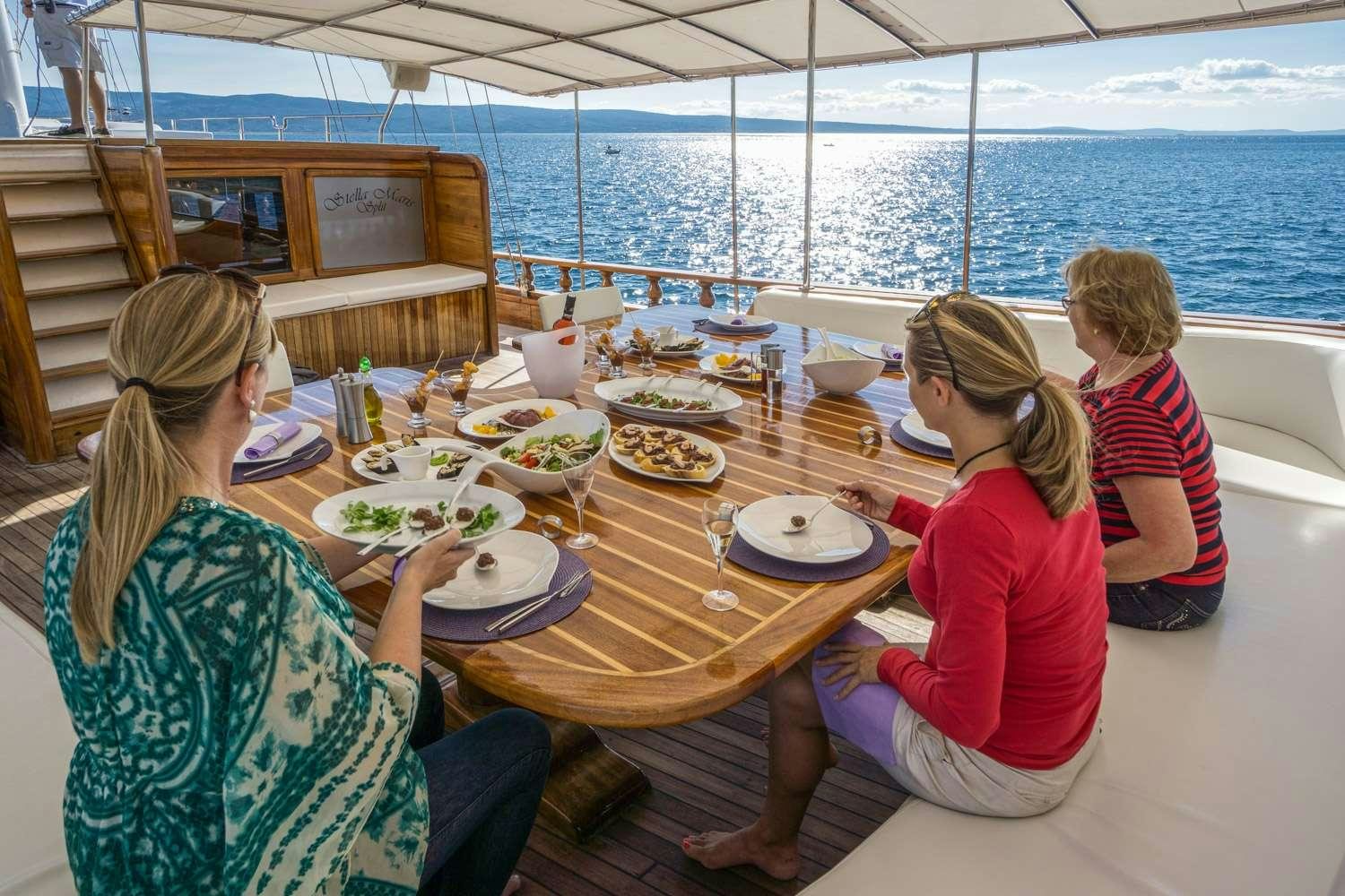 a group of people sitting at a table with food on it aboard STELLA MARIS Yacht for Charter