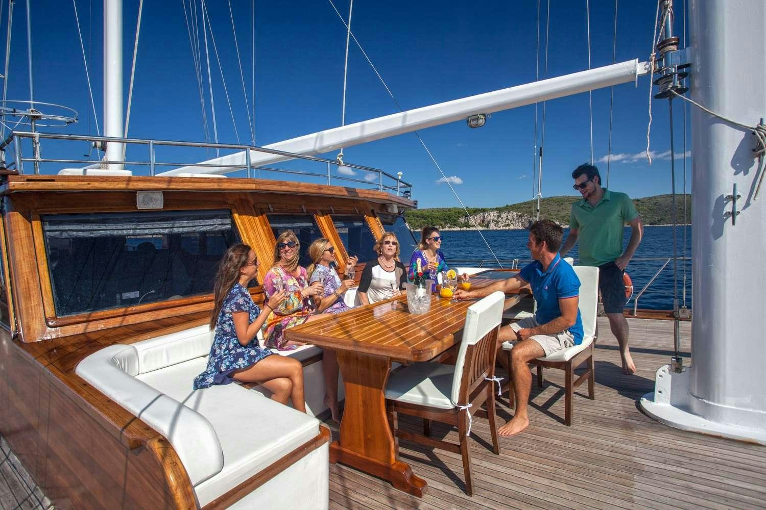 a group of people sitting around a table outside aboard STELLA MARIS Yacht for Charter