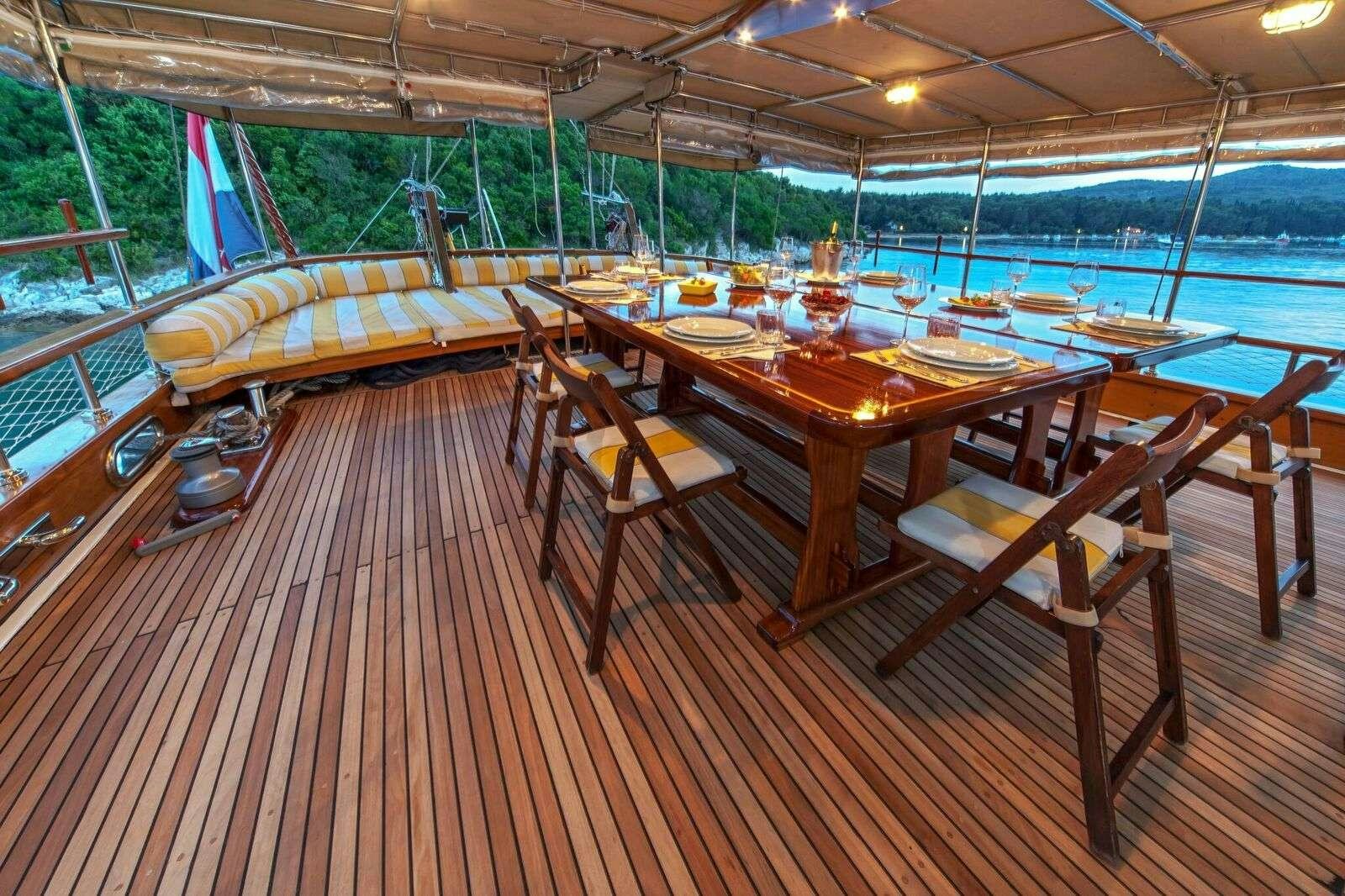 a wooden deck with a table and chairs on it aboard LINDA Yacht for Charter