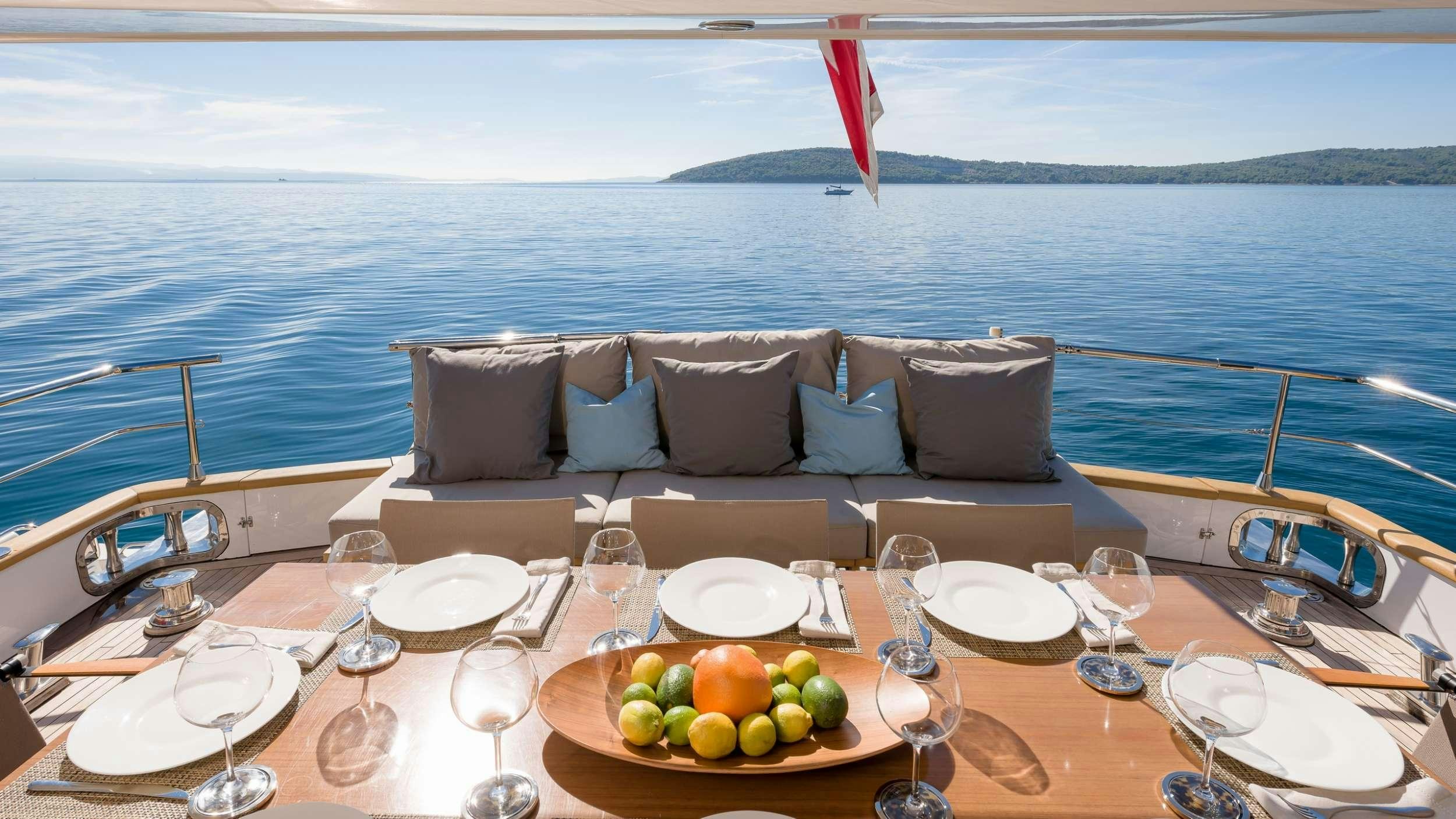 a table with a couch and wine glasses on it aboard MOONRAKER II Yacht for Charter