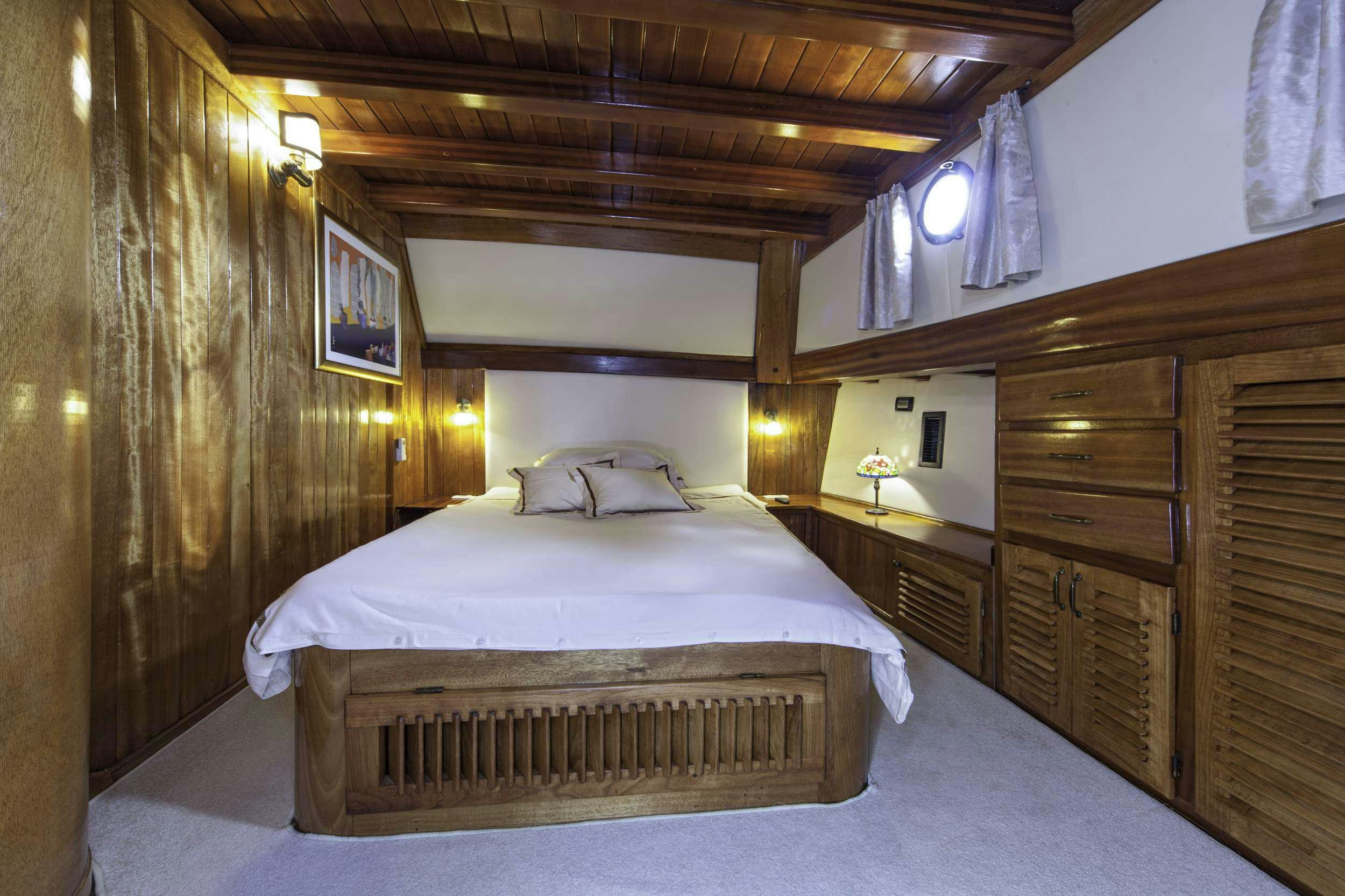 a bed with a white sheet and a wooden headboard aboard LIBRA Yacht for Charter
