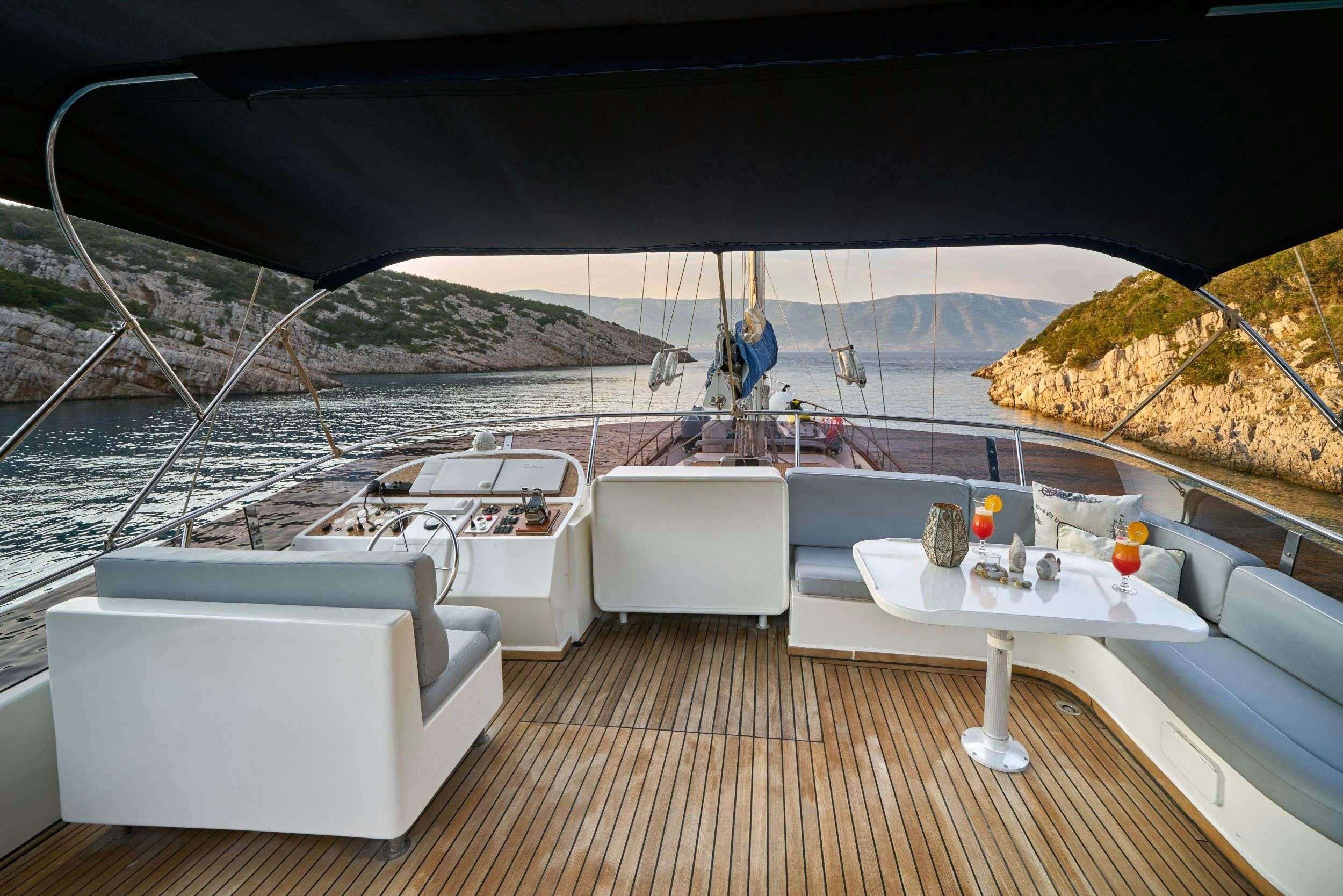 a deck with a view of a large body of water and a large boat on it aboard LOTUS Yacht for Charter