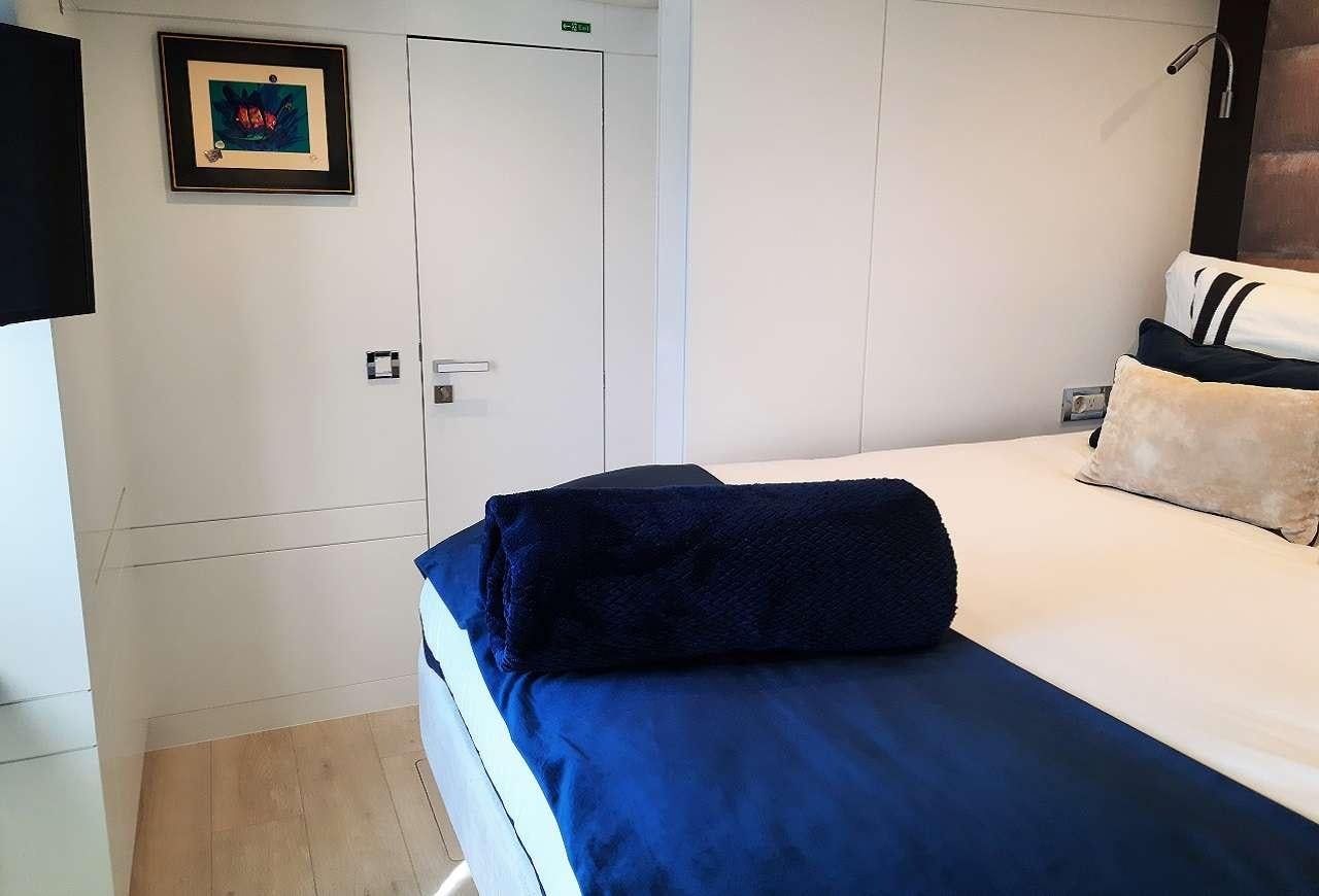 a bed with blue sheets aboard ORION Yacht for Charter