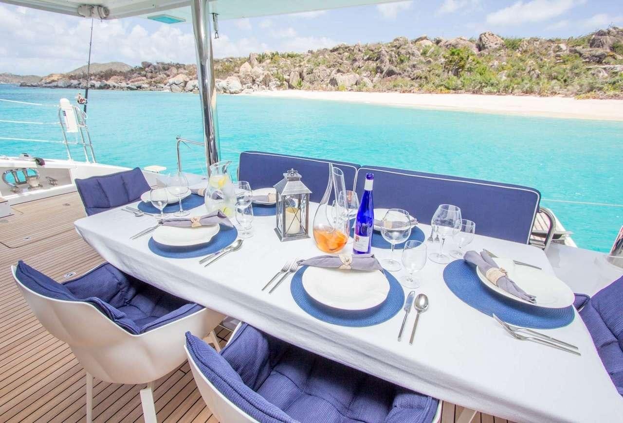 a table set for a meal on a balcony overlooking a beach aboard ORION Yacht for Charter