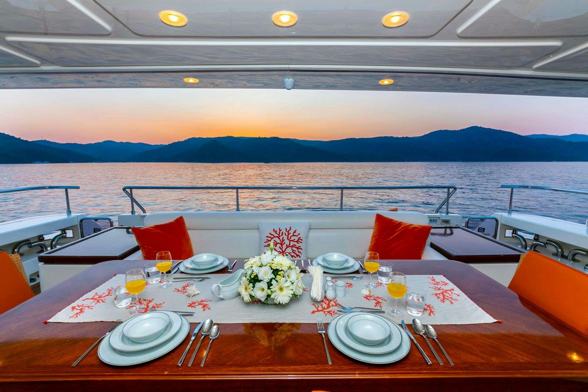 a table with plates and flowers on it by a body of water aboard FUNDA D Yacht for Charter
