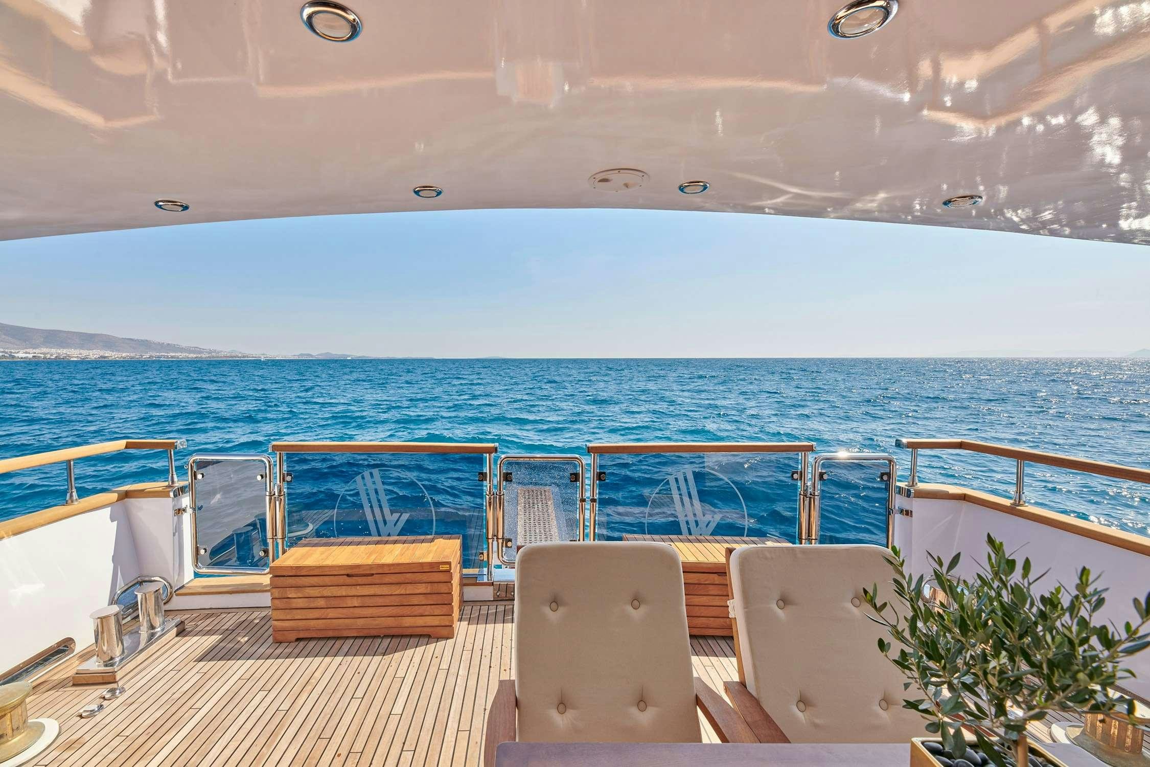 a deck with chairs and a body of water in the background aboard WIDE LIBERTY Yacht for Charter