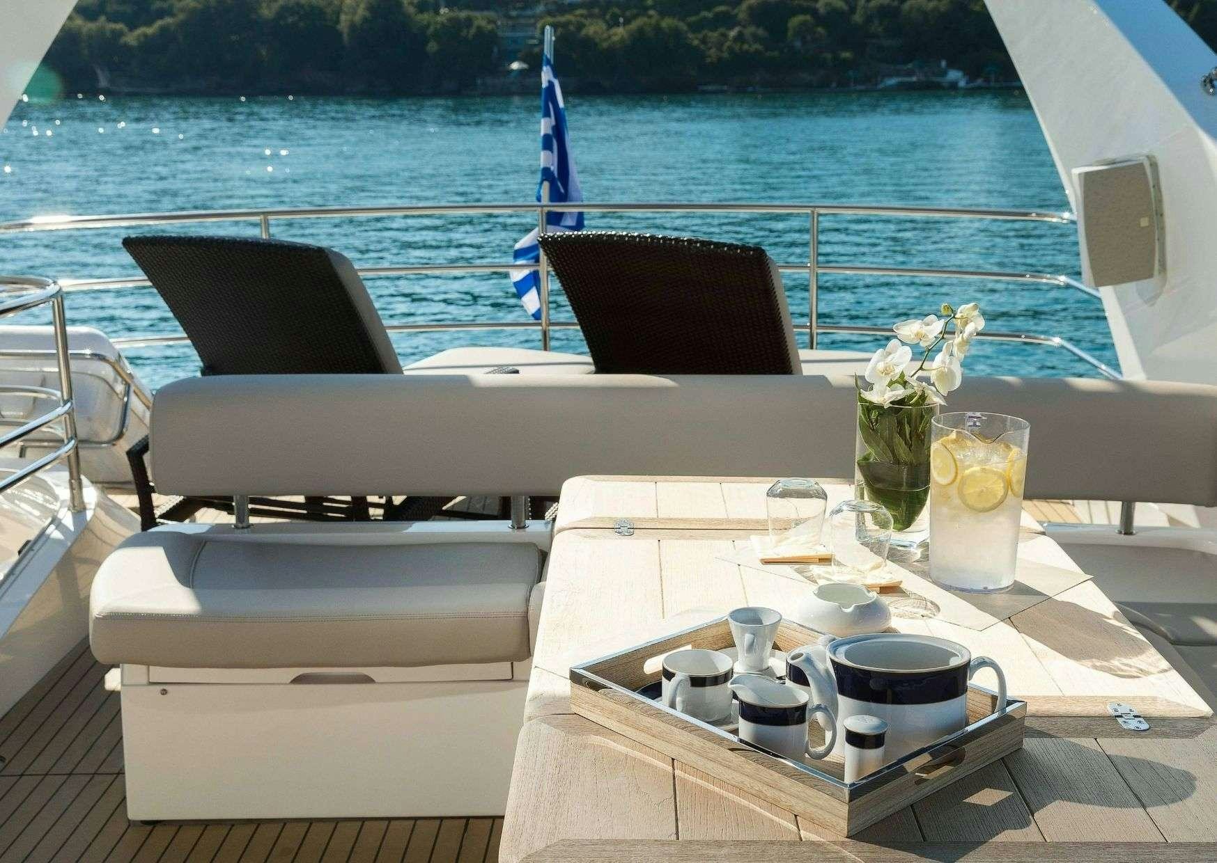 a table with cups and plates on it next to a body of water aboard SHINE Yacht for Charter