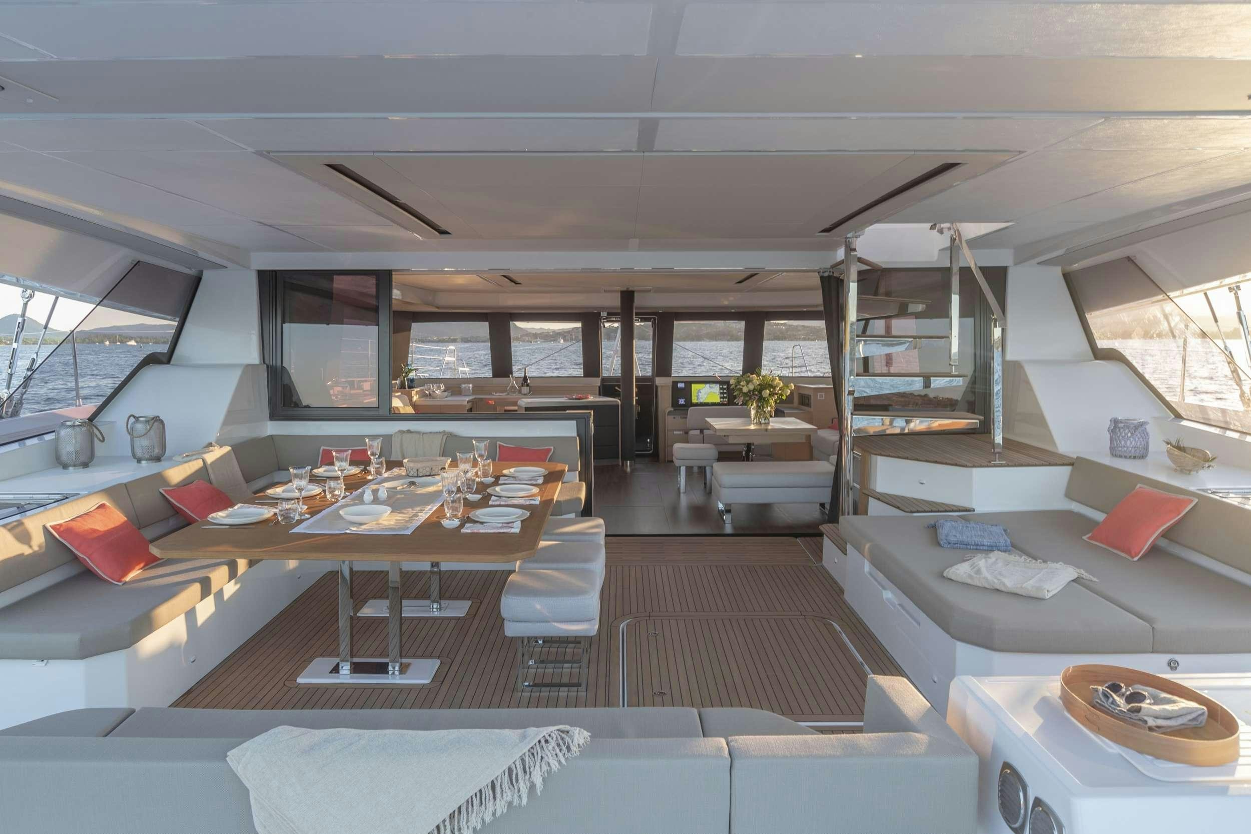a room with a large window and a table with chairs and a couch aboard KIMATA Yacht for Charter