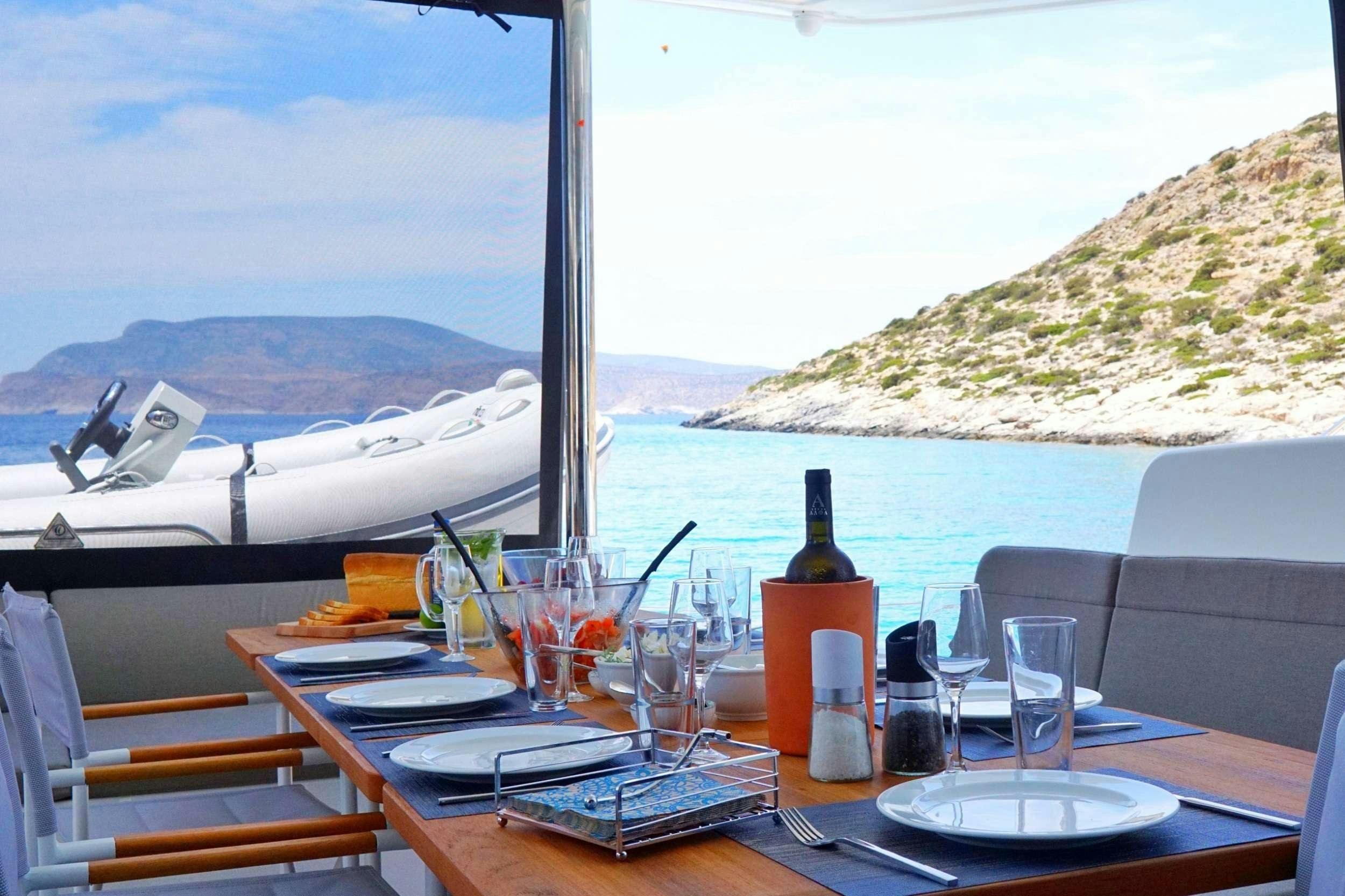 a table with plates and glasses on it next to a boat aboard ANDIAMO Yacht for Charter