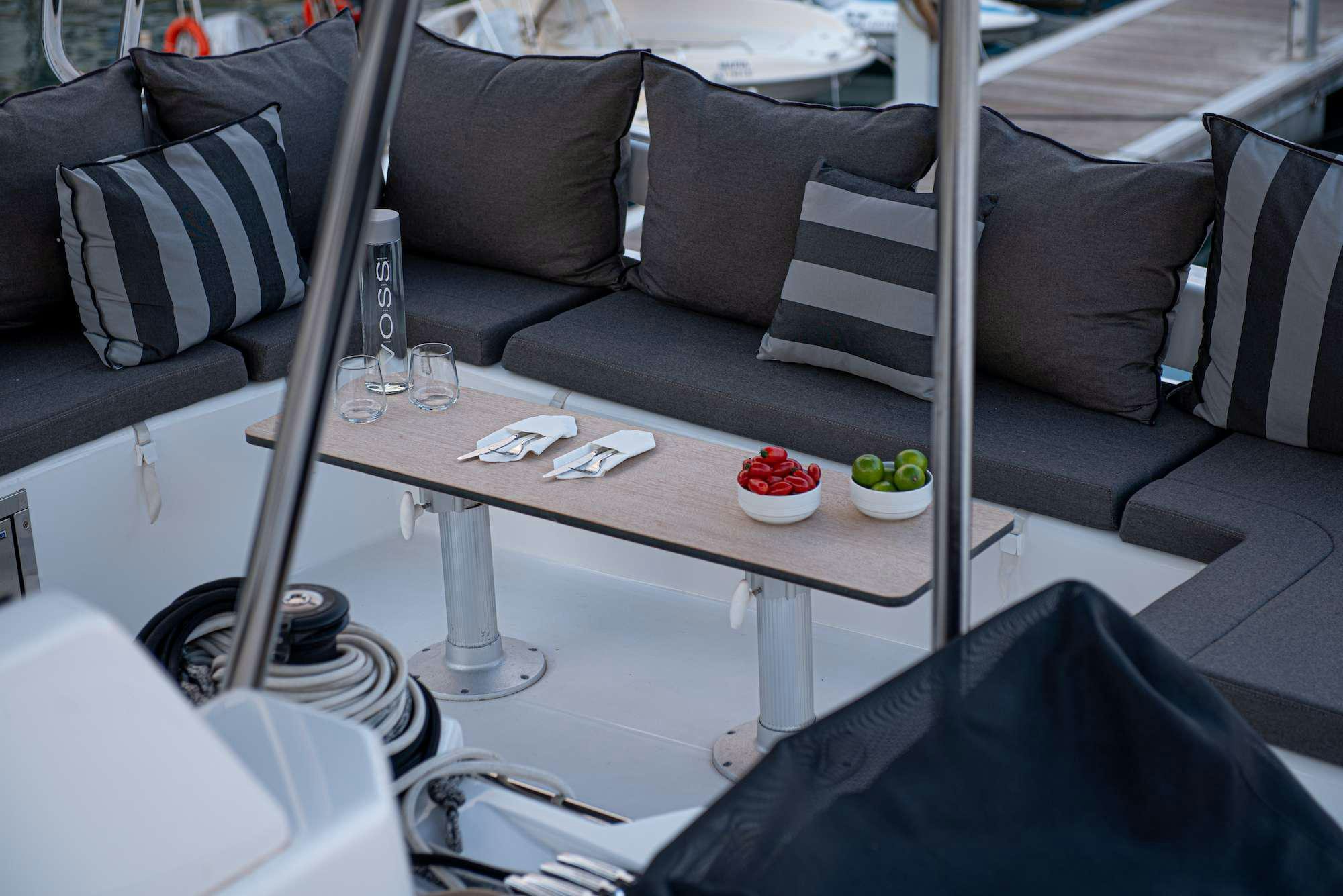 a table with a glass and a chair with a couch and a coffee table aboard MY BLUE HEAVEN Yacht for Charter