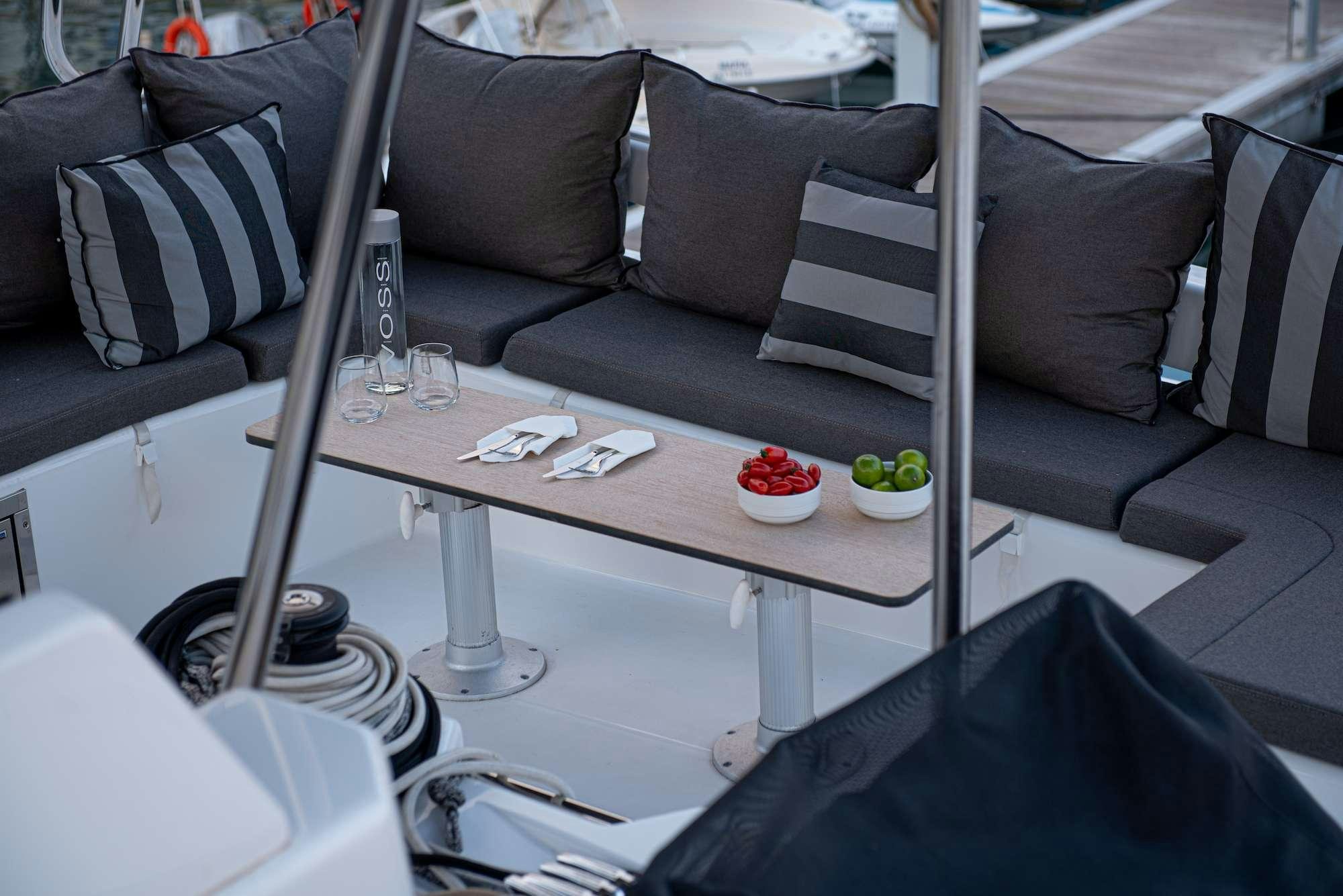 a table with a glass and a chair with a couch and a coffee table aboard MY BLUE HEAVEN Yacht for Charter