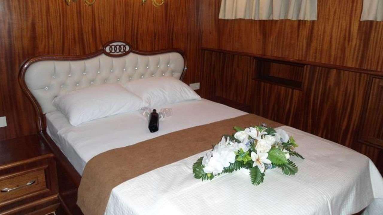 a bed with white sheets and flowers aboard M/S E.ARDA DENIZ Yacht for Charter
