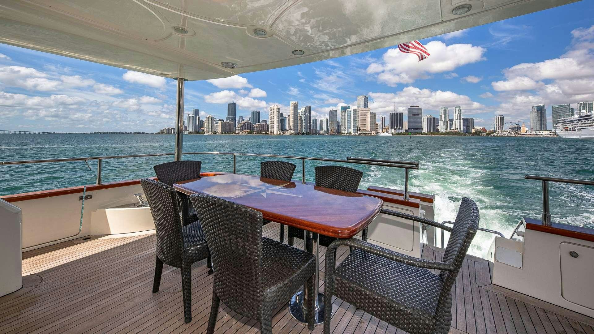 a table and chairs on a deck overlooking a city aboard grace Yacht for Charter
