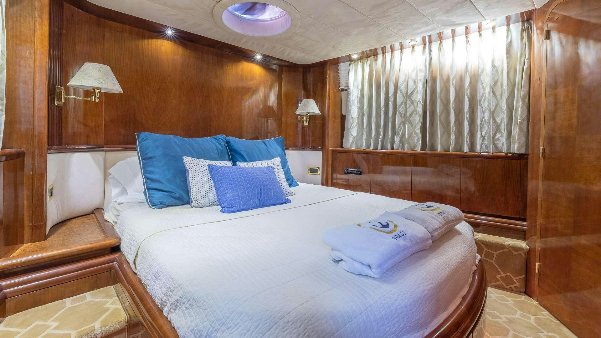 a bed with blue pillows aboard grace Yacht for Charter