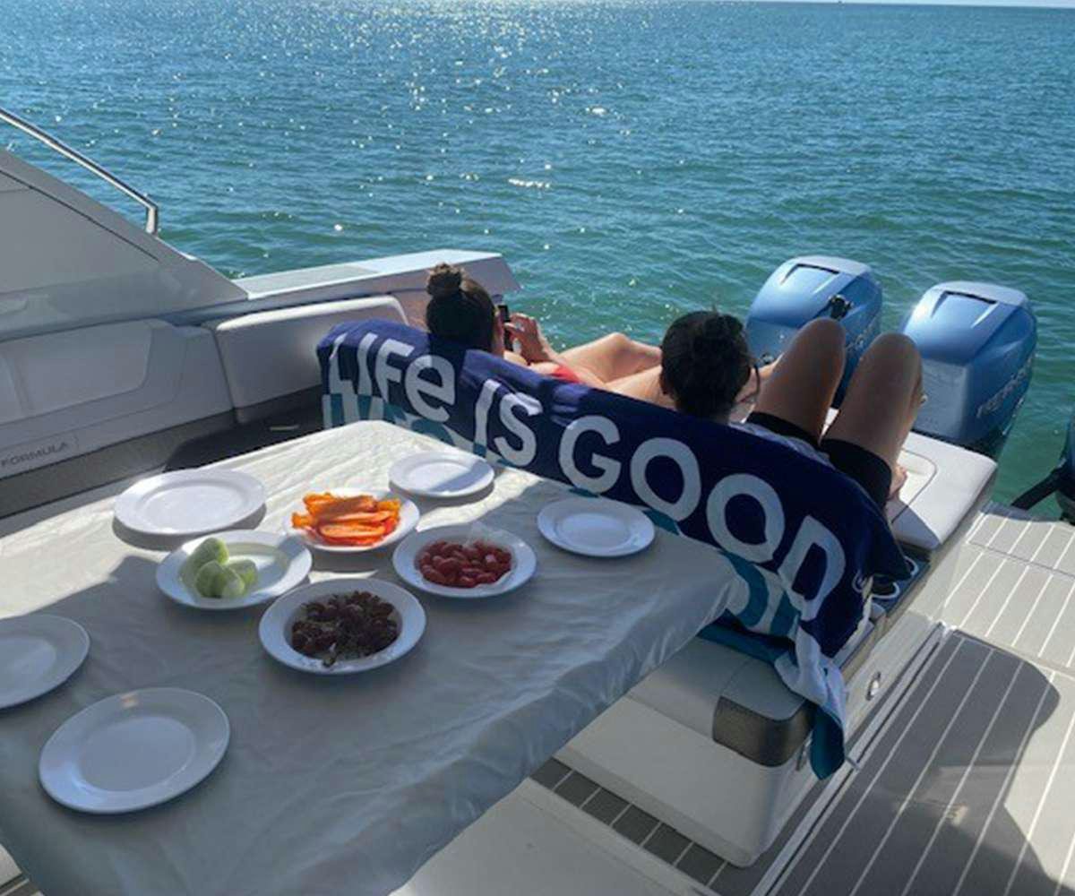 a person lying on a table on a boat with plates and food on it aboard Life Is Good Yacht for Charter