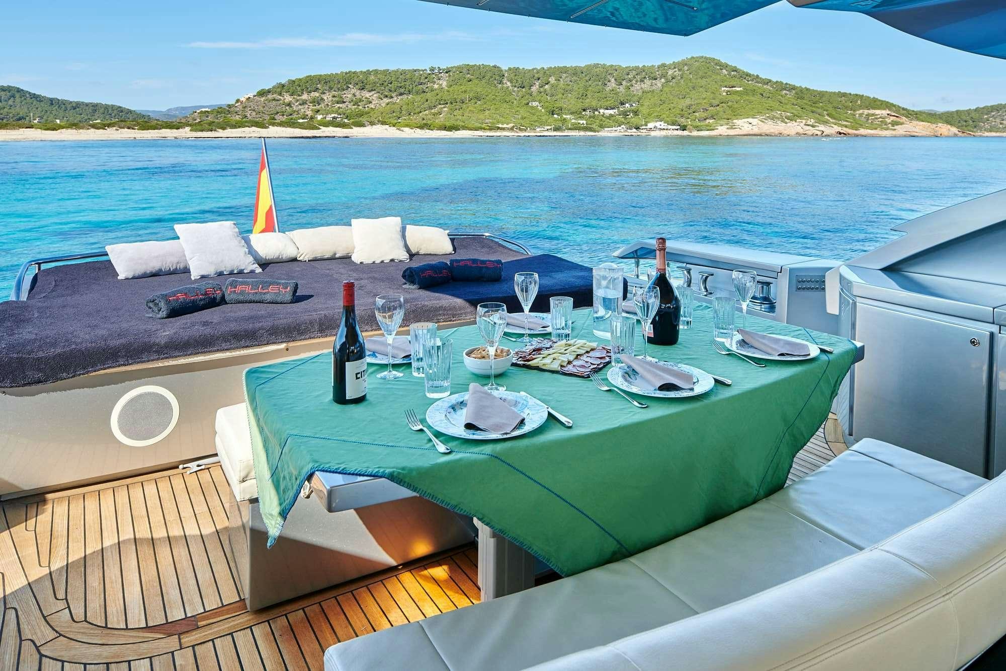 a table with wine bottles and glasses on it by a body of water aboard HALLEY Yacht for Charter