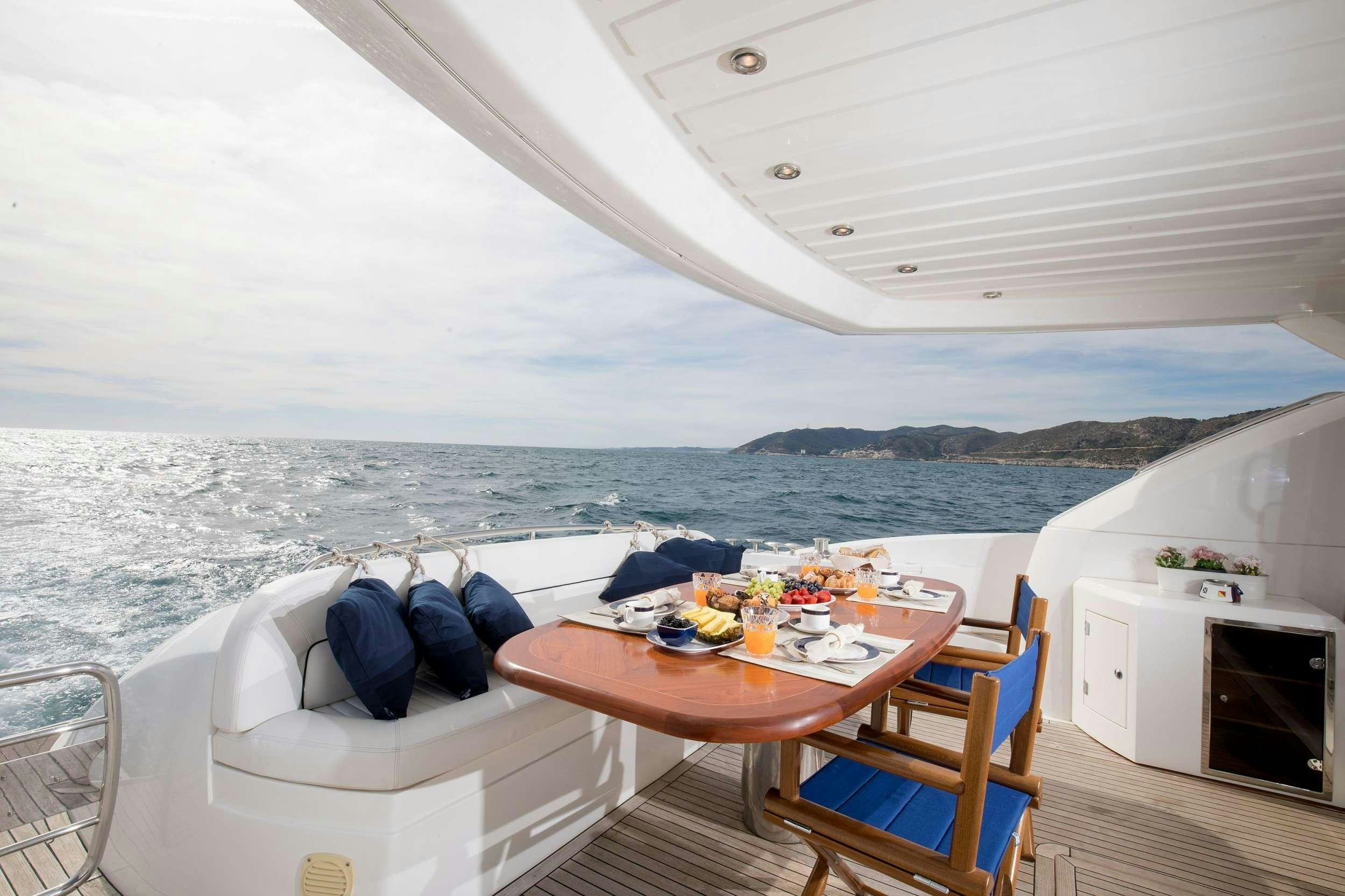 a table with chairs on it next to a large body of water aboard MEDITERRANI IV Yacht for Charter