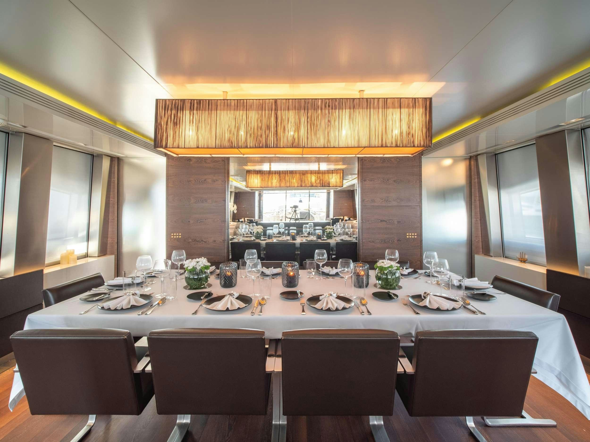 a large dining table with empty chairs aboard M Yacht for Charter