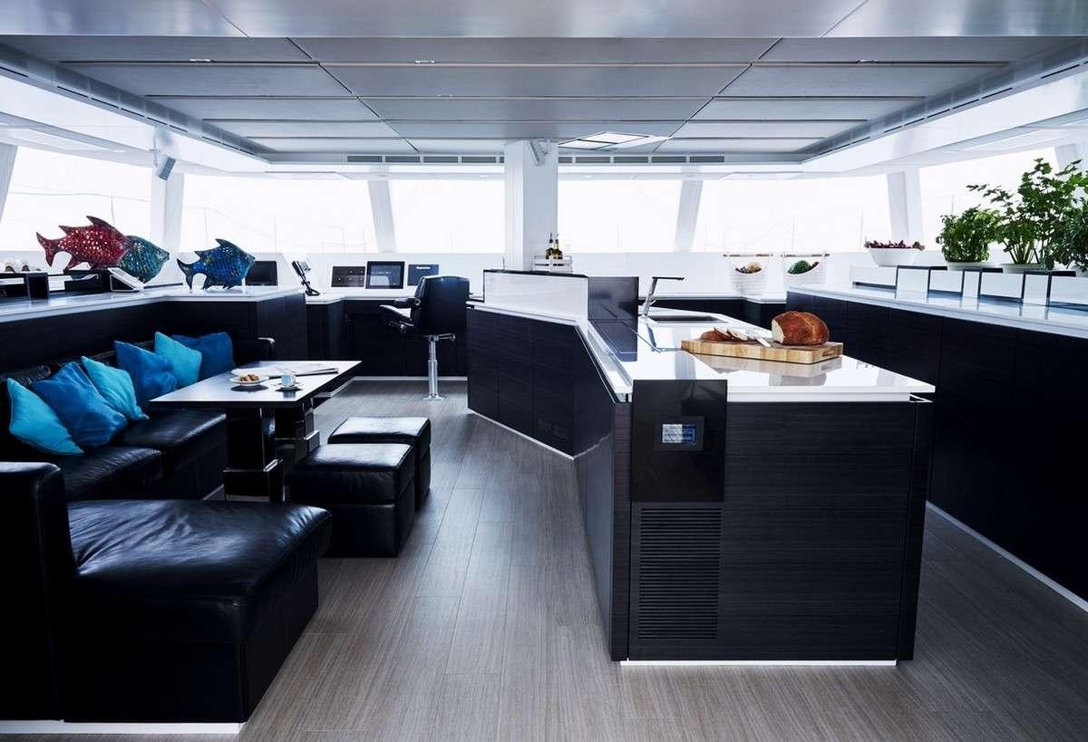 a room with black couches and a wood table aboard 19TH HOLE Yacht for Charter