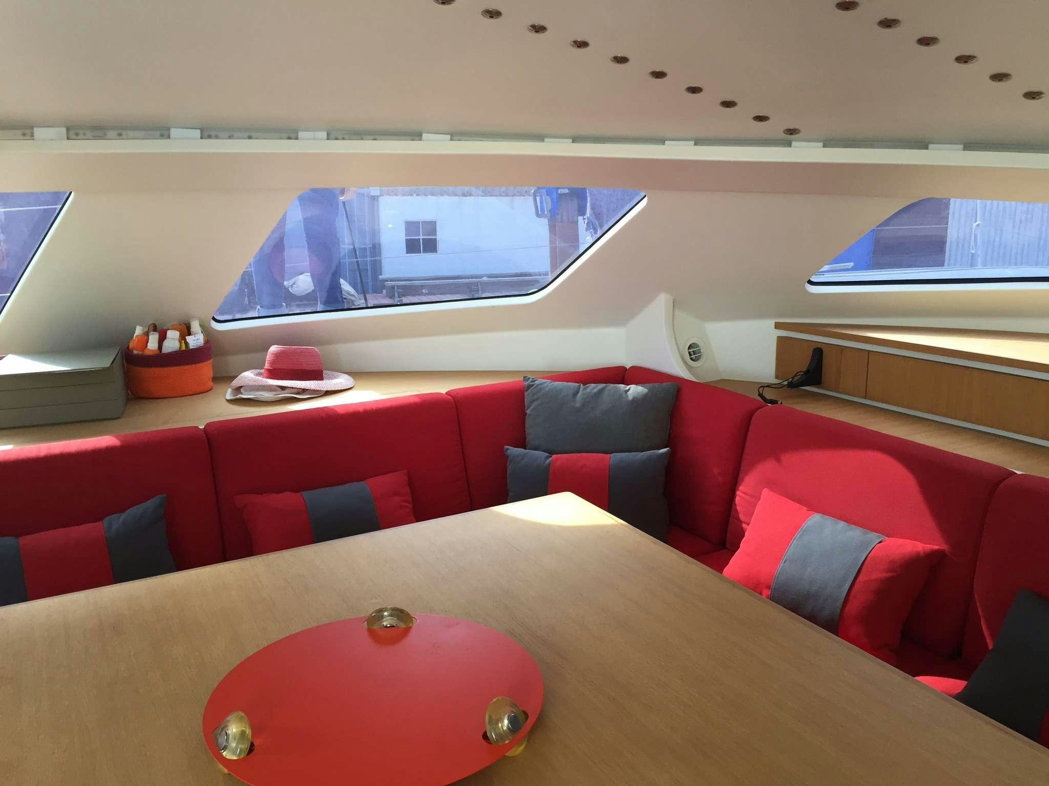 a room with red seats and a table with a red and white tablecloth with a red plate aboard Obi One Yacht for Charter