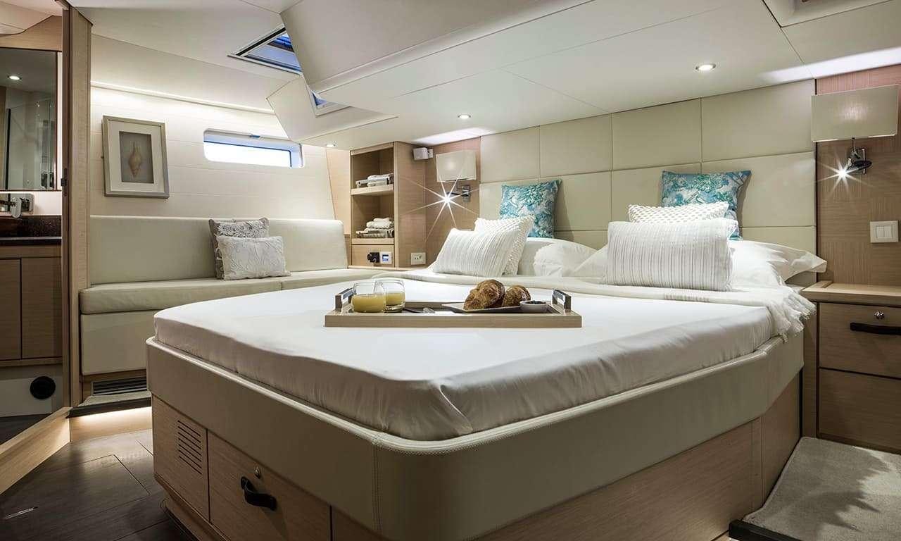 a bed with white sheets and pillows aboard THEA Yacht for Charter