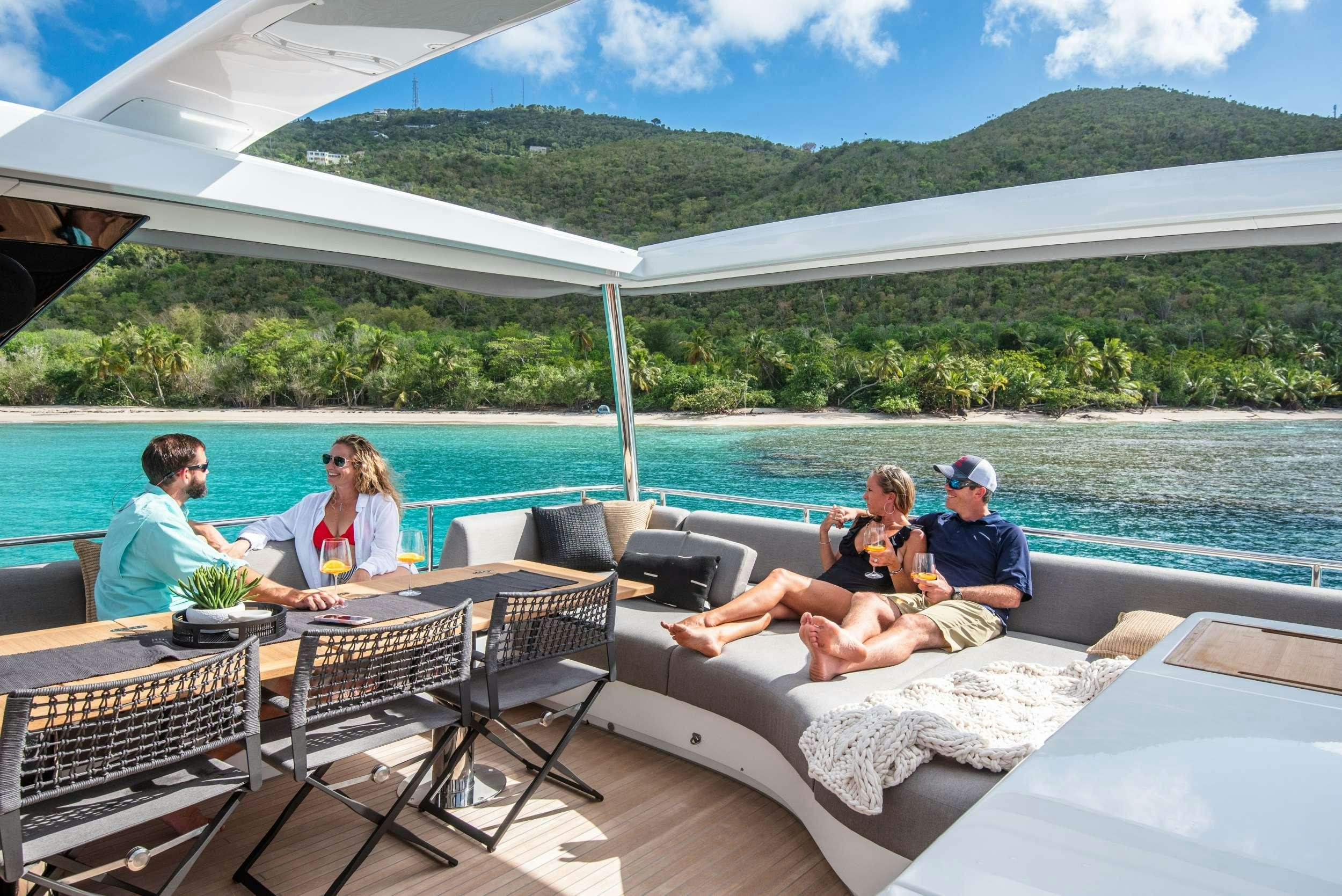 a group of people sitting on a couch on a deck overlooking a body of water aboard C’EST LA VIE Yacht for Charter
