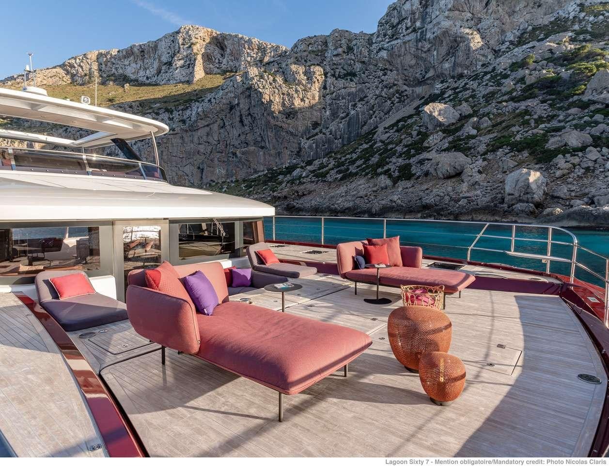 a pool with lounge chairs and a mountain in the background aboard C’EST LA VIE Yacht for Charter