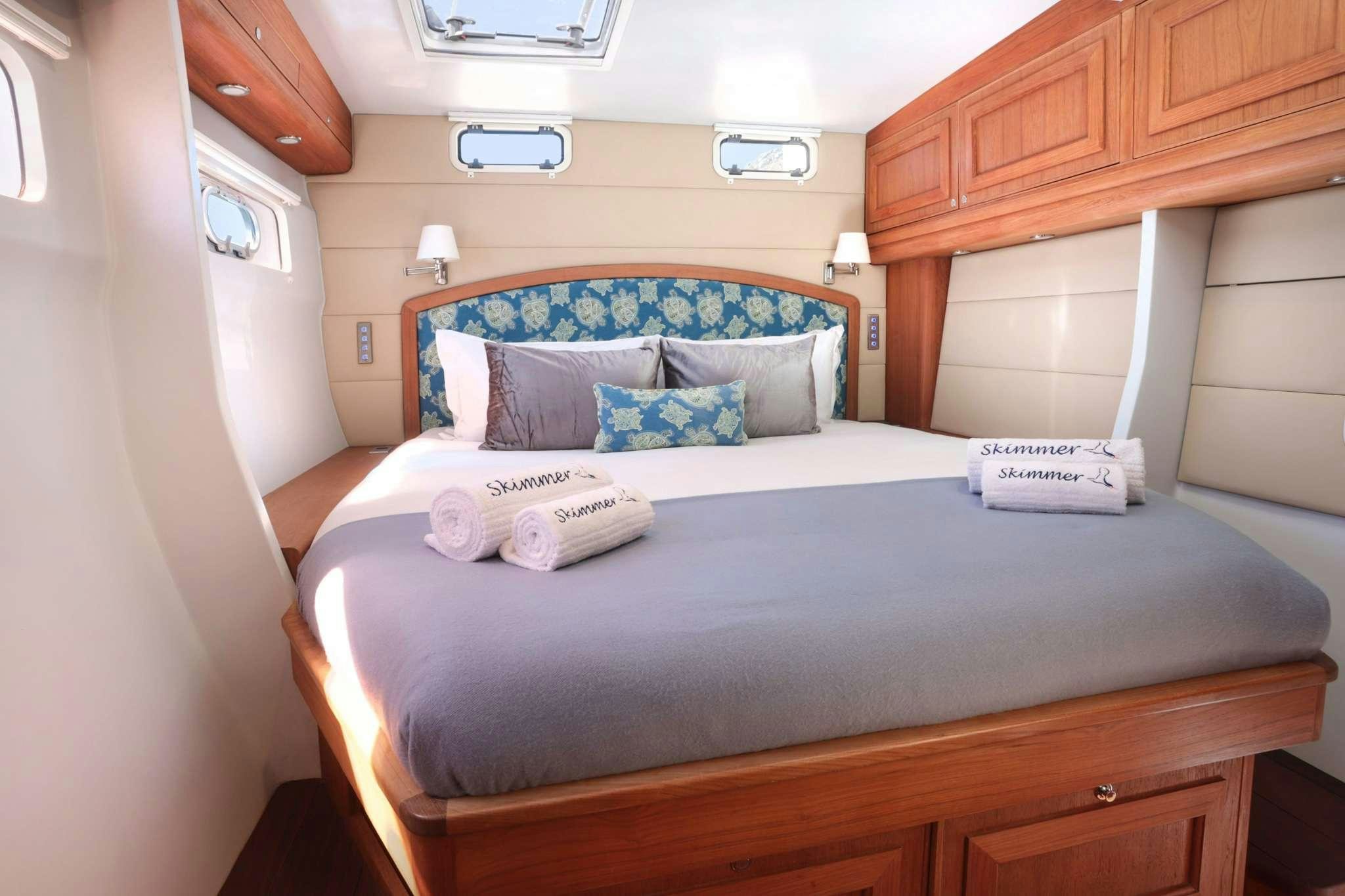 a bed with a blue and white comforter and pillows aboard SKIMMER Yacht for Charter