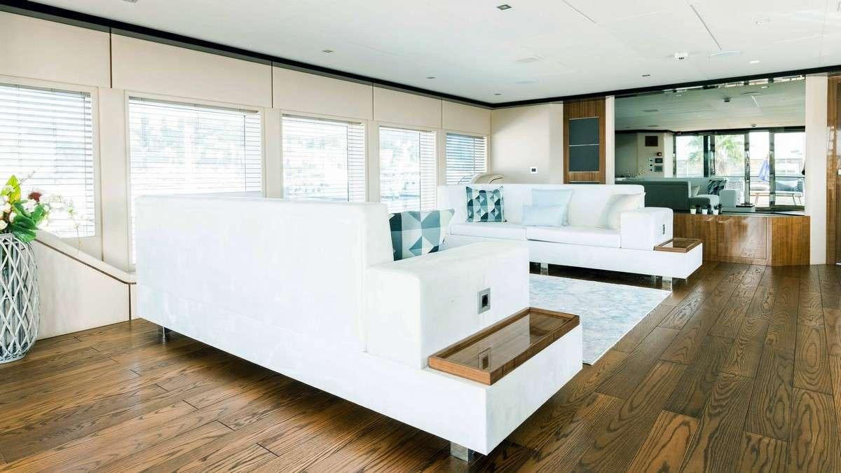 a living room with a large white couch and a large window aboard LADY CAROLINE Yacht for Charter
