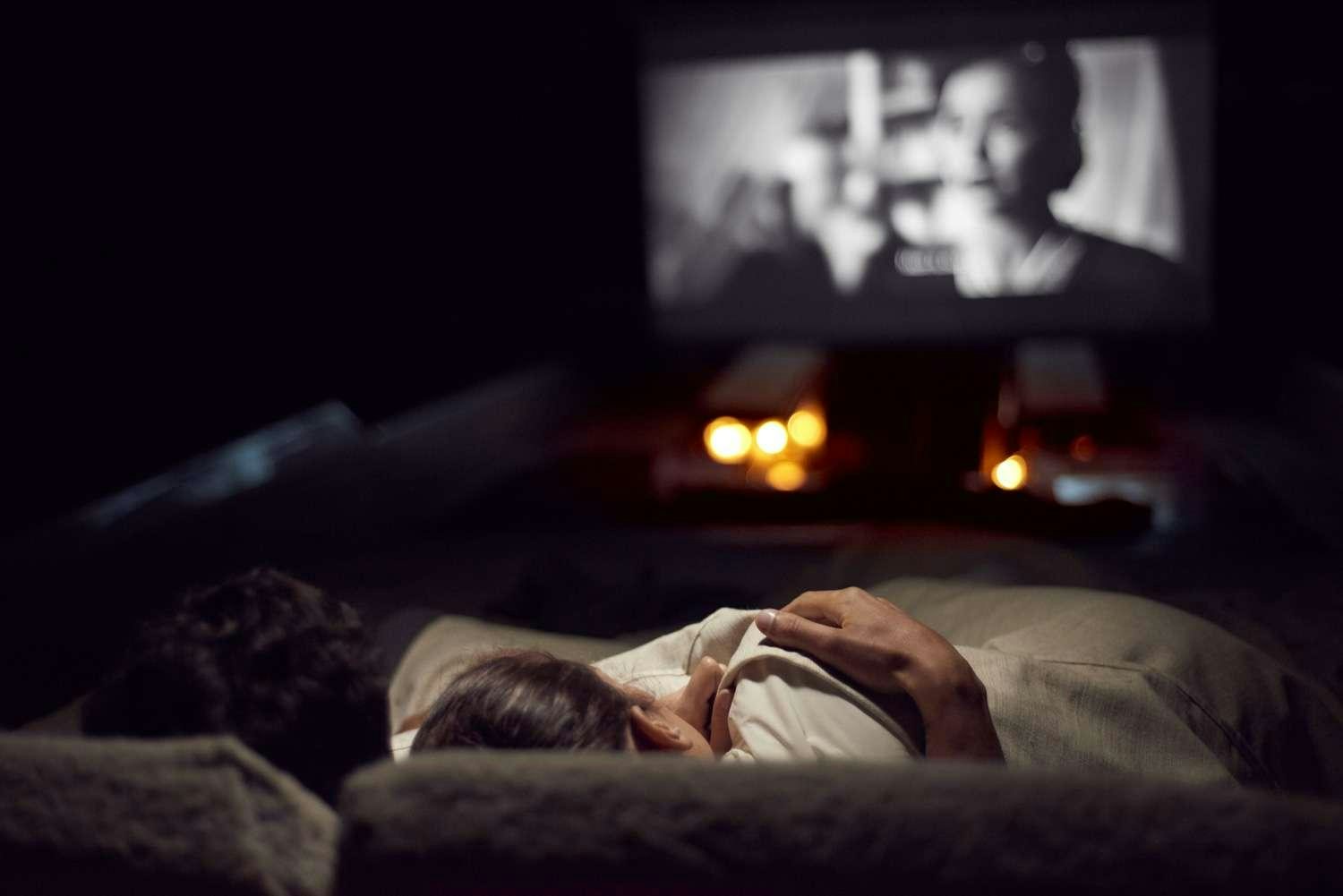 a person lying on a bed watching a television aboard AORI Yacht for Charter